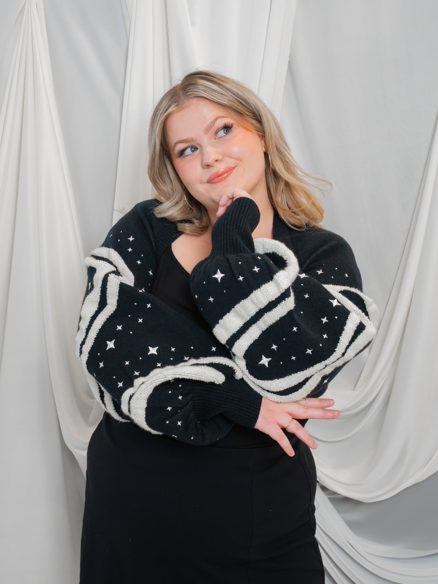 Woman posing wearing black and white deep space bolero in size large in front of white fabric draped background