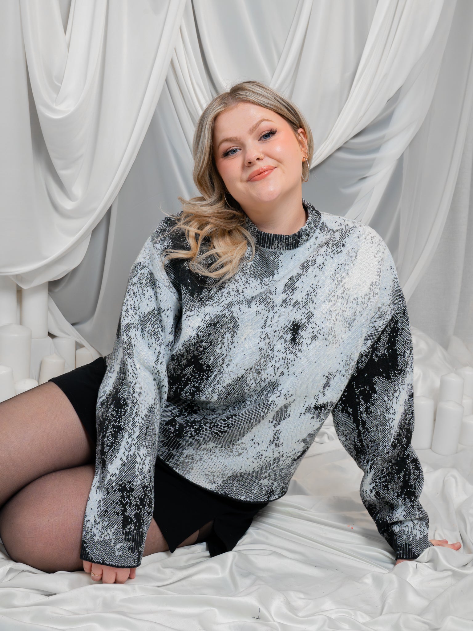 Woman posing on ground wearing white, grey and black cropped knit lunar sweater in size large.
