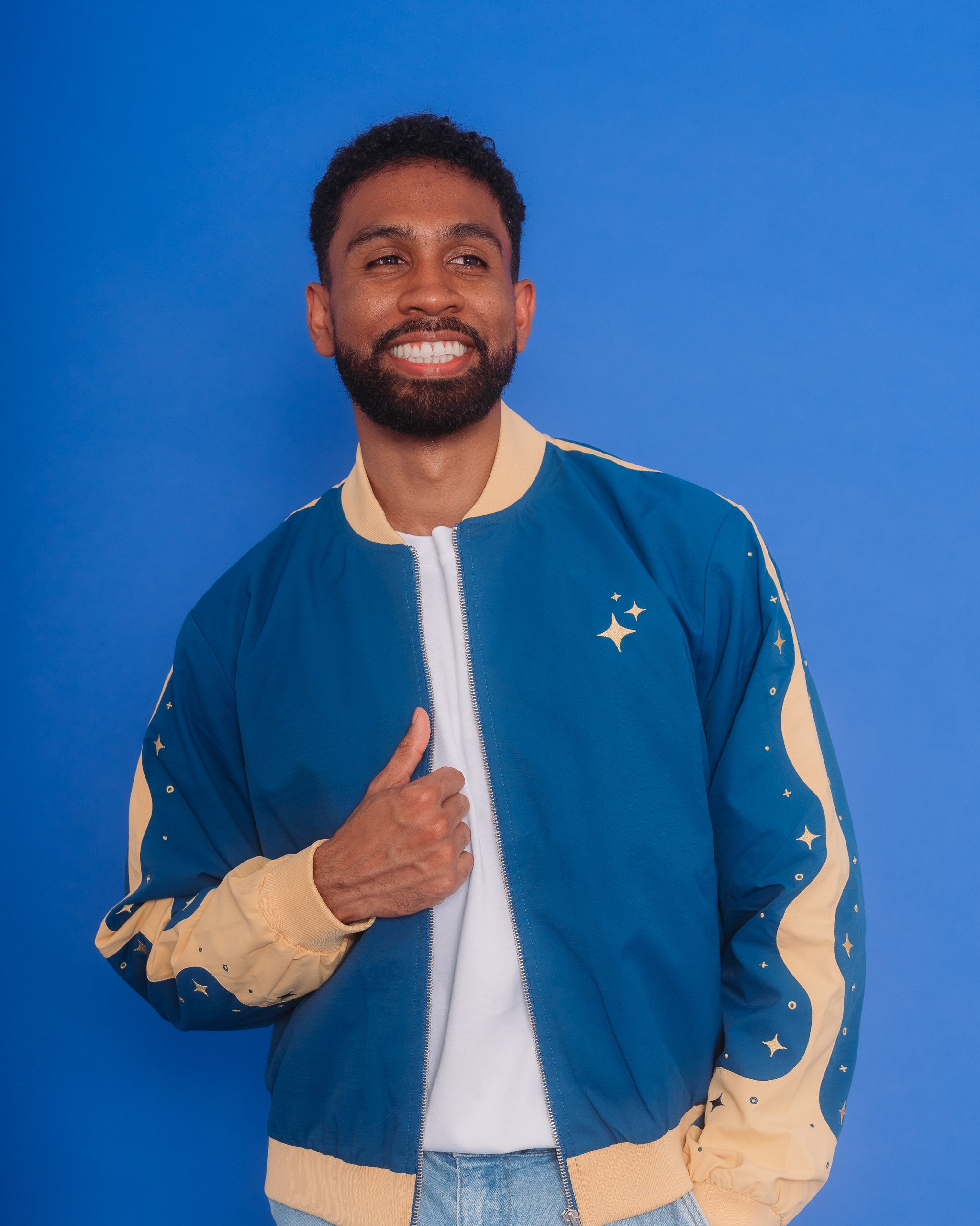Man wearing blue moon bomber jacket in size extra large in front of blue background.