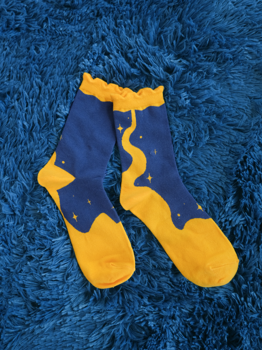 Pair of blue moon socks laying flat on a fuzzy blue background.