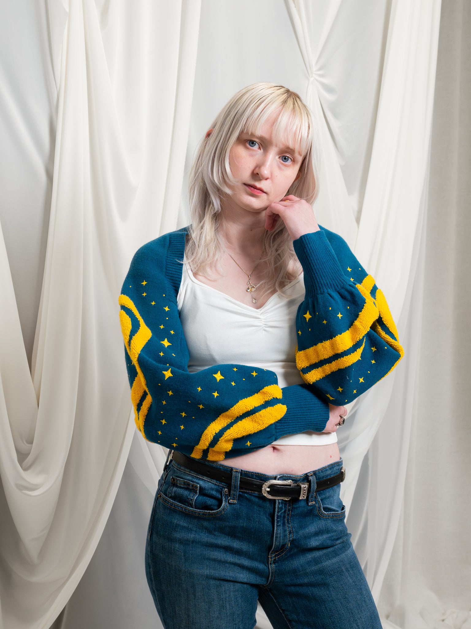 Woman wearing blue and yellow blue moon bolero in size extra small with supernova cap sleeve tee in front of white draped fabric.