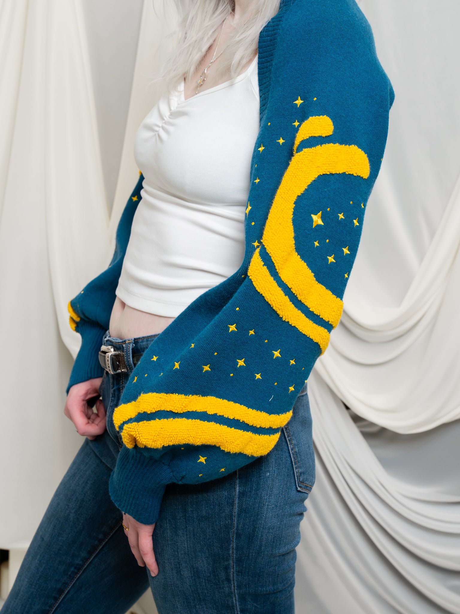 Sleeve close up of blue and yellow blue moon bolero showcasing yellow wavy detail and embroidered yellow sparkles.