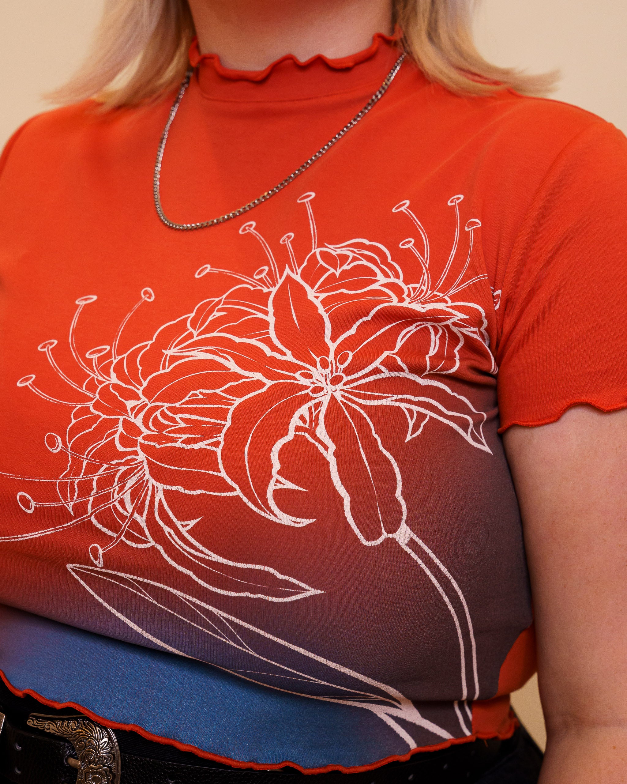 Close up of red mini calling card tee showing screen printed floral design.