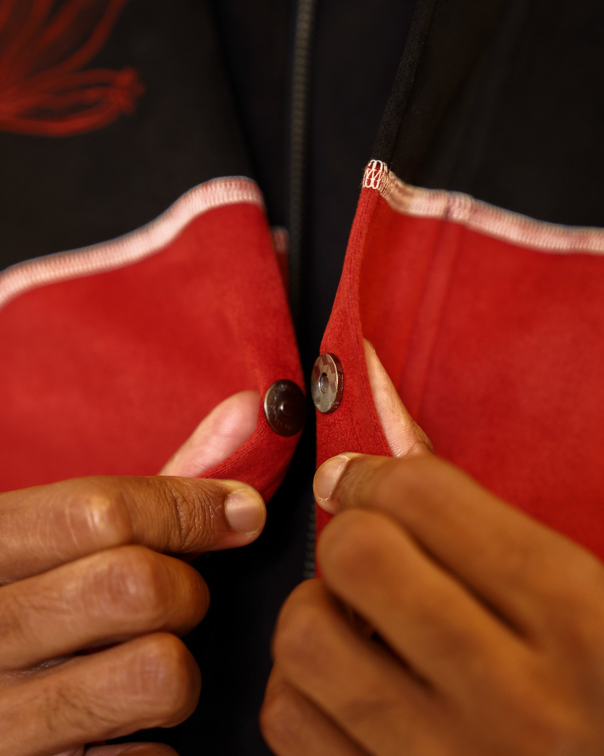 Close up of calling card faux-suede jacket magnetic snap button closure.