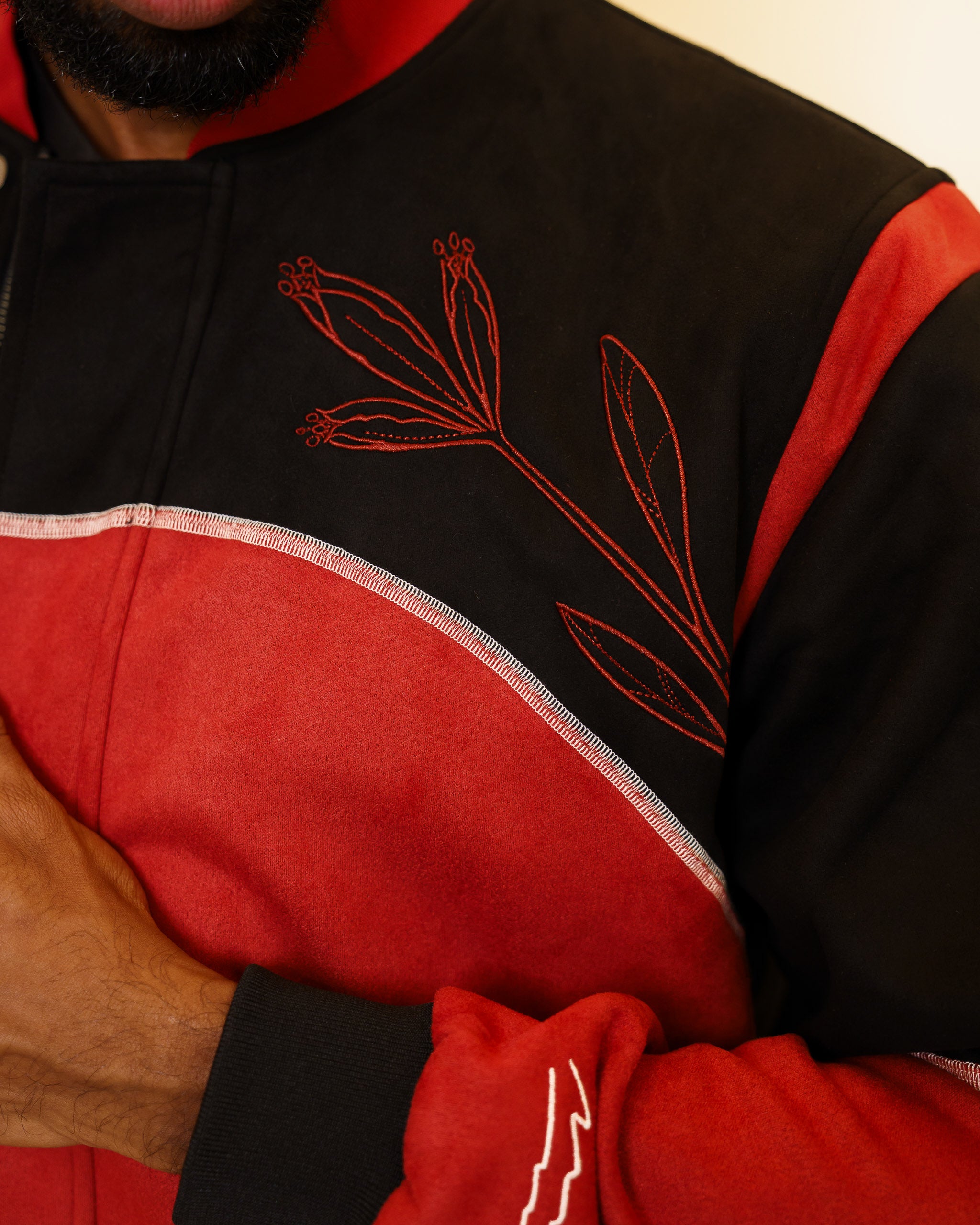 Close up of calling card faux-suede jacket red embroidered flower detail on chest.