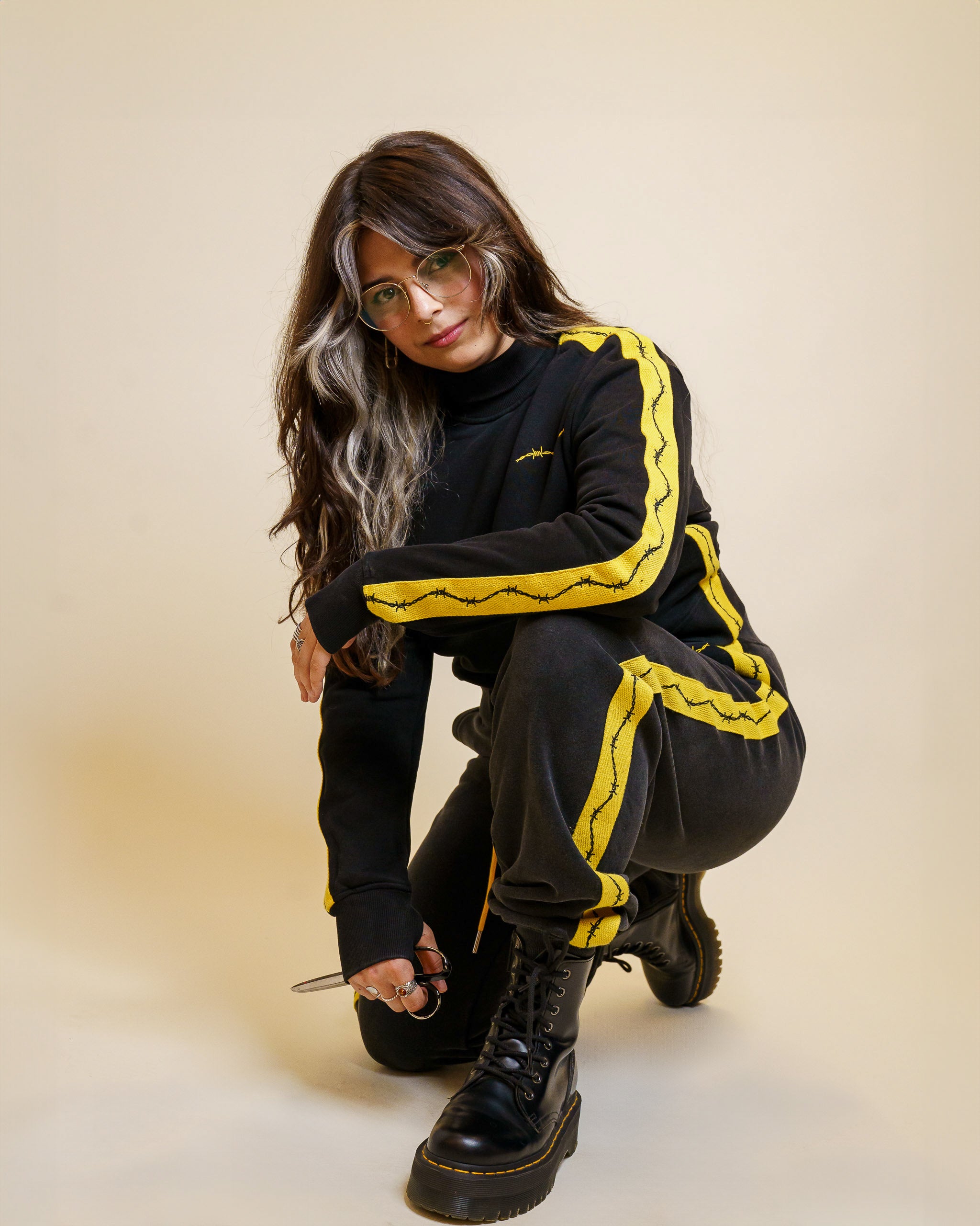 Woman crouching down wearing caution cropped mock neck in size small and caution joggers.