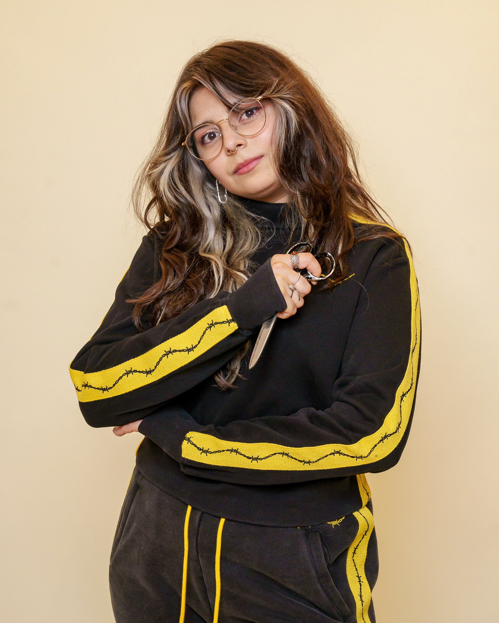 Woman wearing caution cropped mock neck in size small holding scissors.