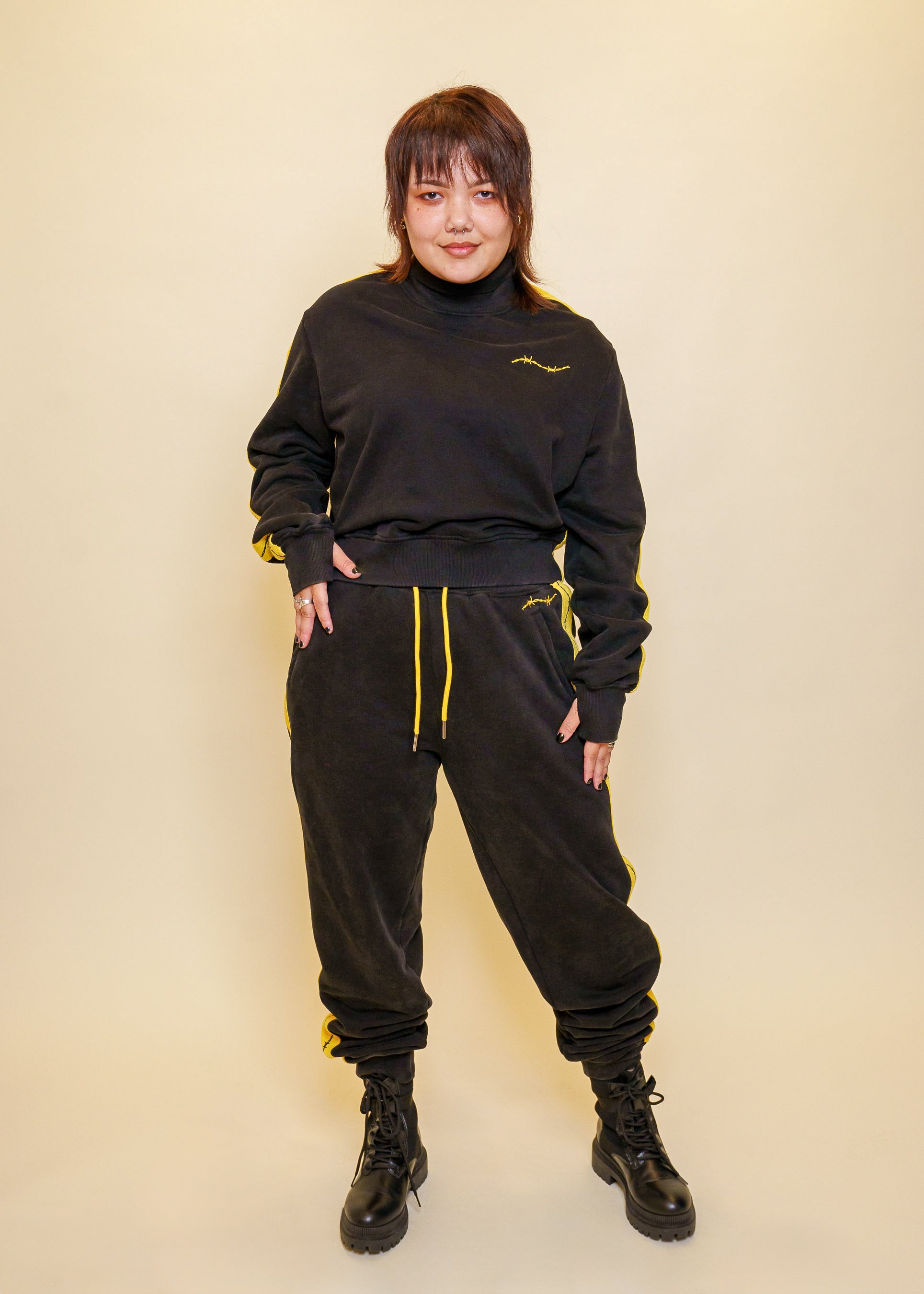 Woman wearing caution joggers in size large with caution sweater in front of off-white background.