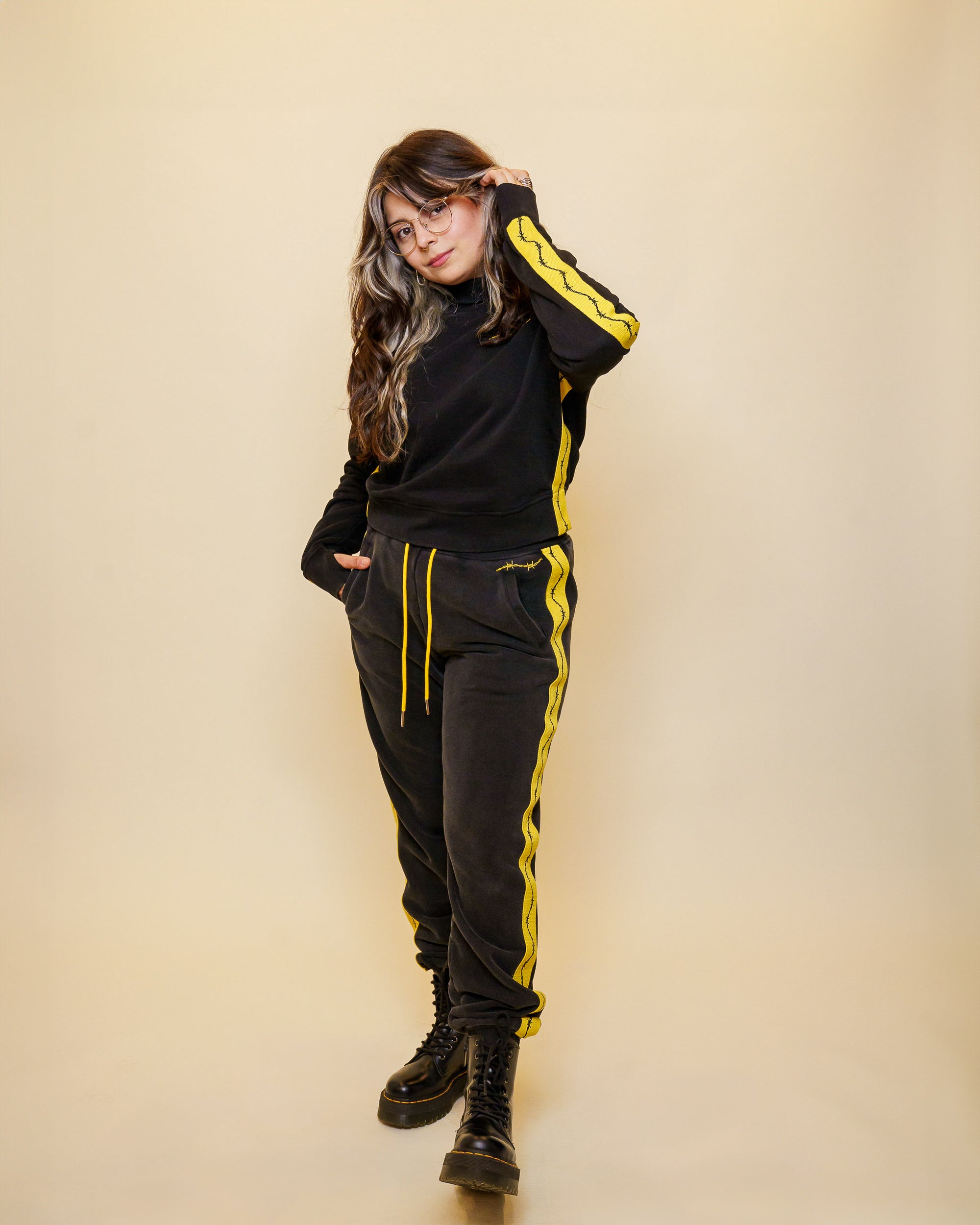 Woman wearing caution joggers in size medium with caution sweater in front of off-white background.