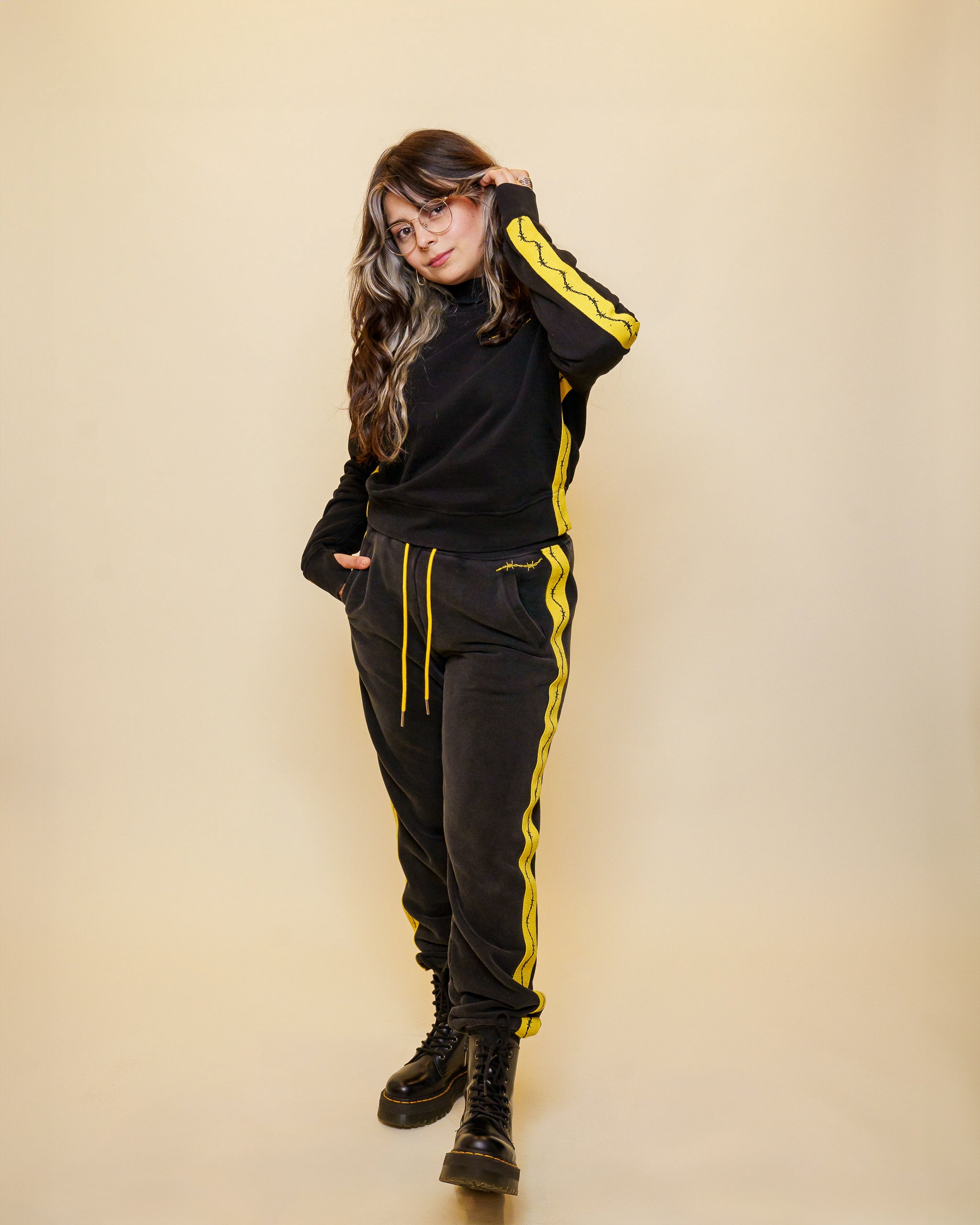 Woman wearing caution joggers in size medium with caution sweater in front of off-white background.