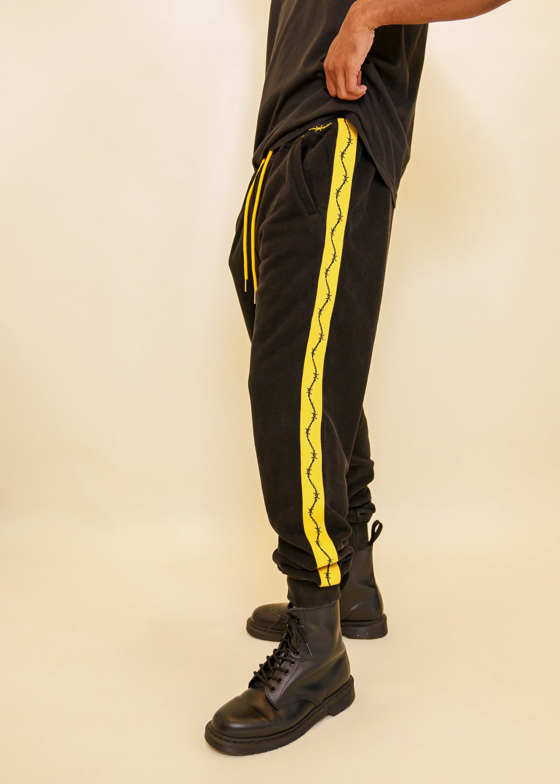 Man wearing caution joggers in size large showing the side stripe with barbed wire graphic going downwards.