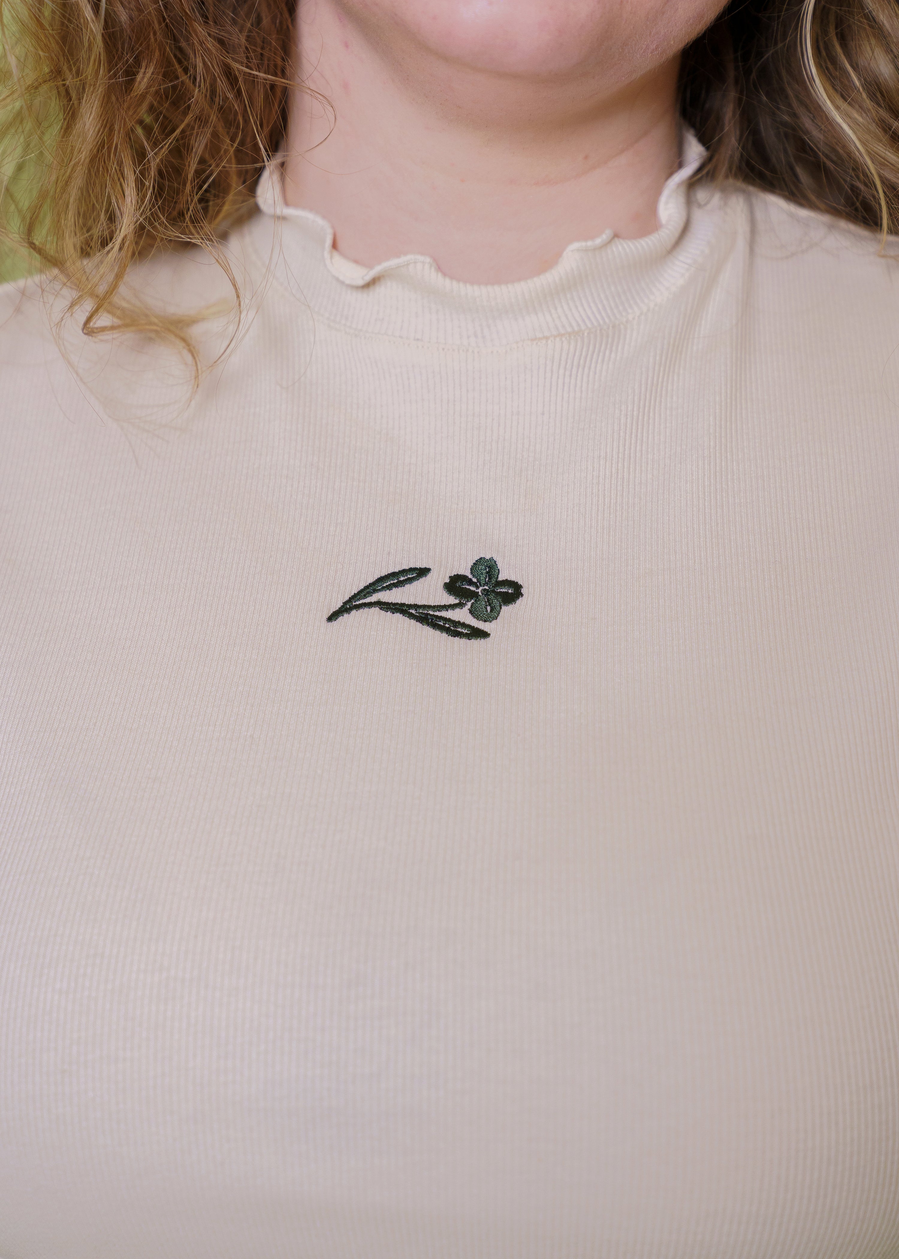Close up of chamomile mini tee embroidered flower on front.