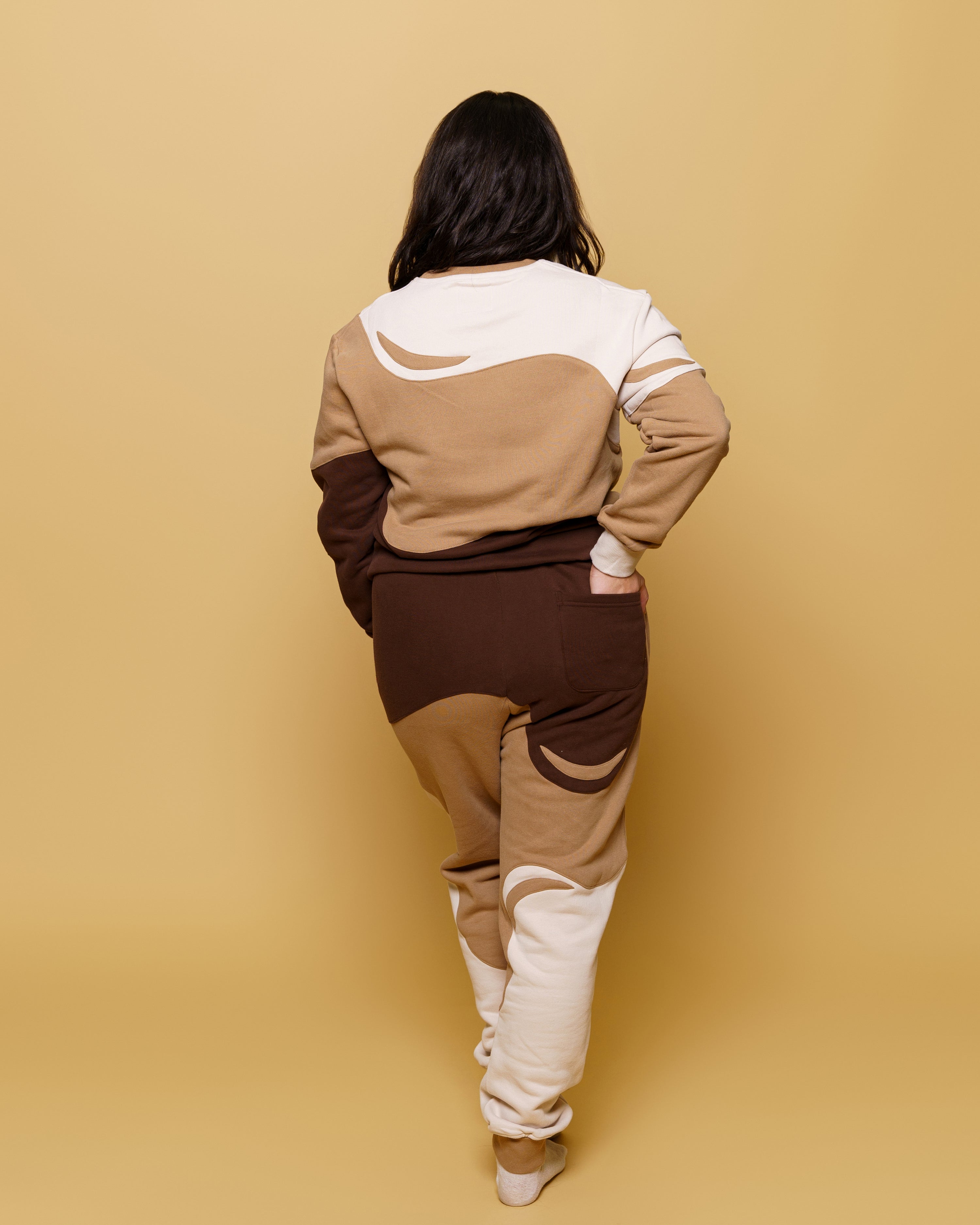 Back view of woman wearing cold brew joggers in size small in front of soft yellow background.