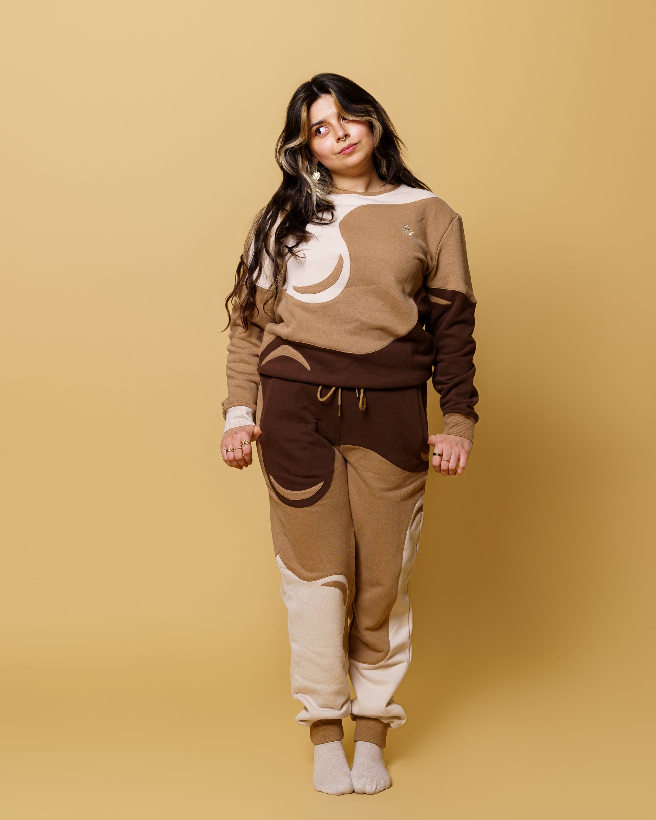 Woman wearing cold brew joggers in size small with cold brew crewneck in front of soft yellow background.