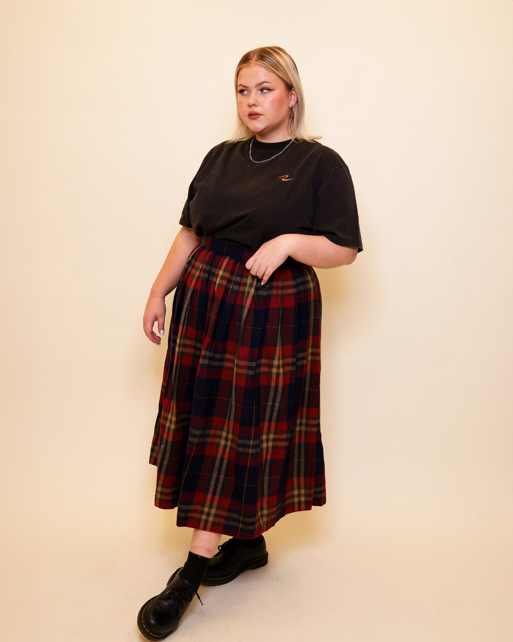 Woman wearing cold case tee in size 48 with plaid long skirt.
