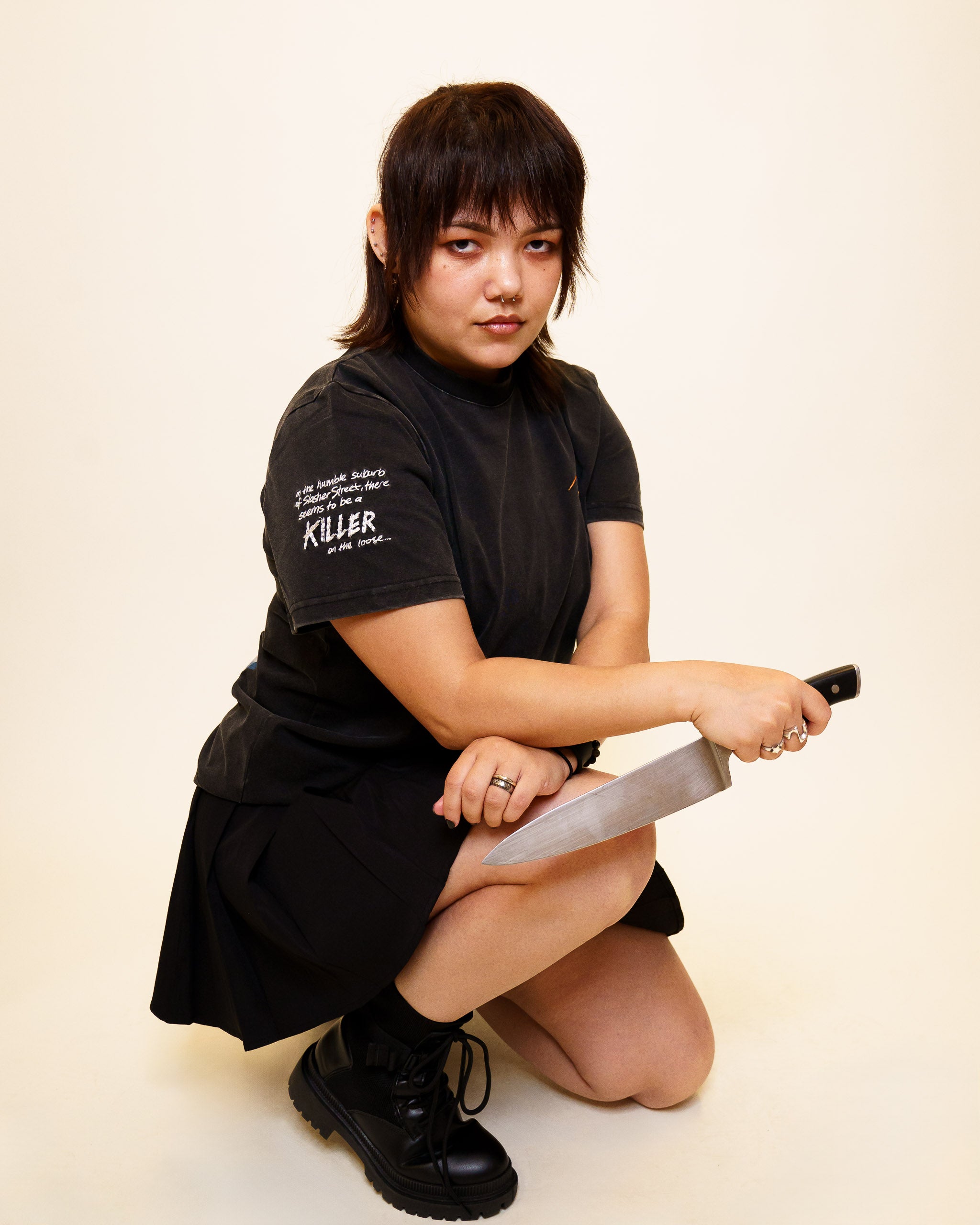 Woman wearing cold case tee in size 42 kneeling down holding a knife.