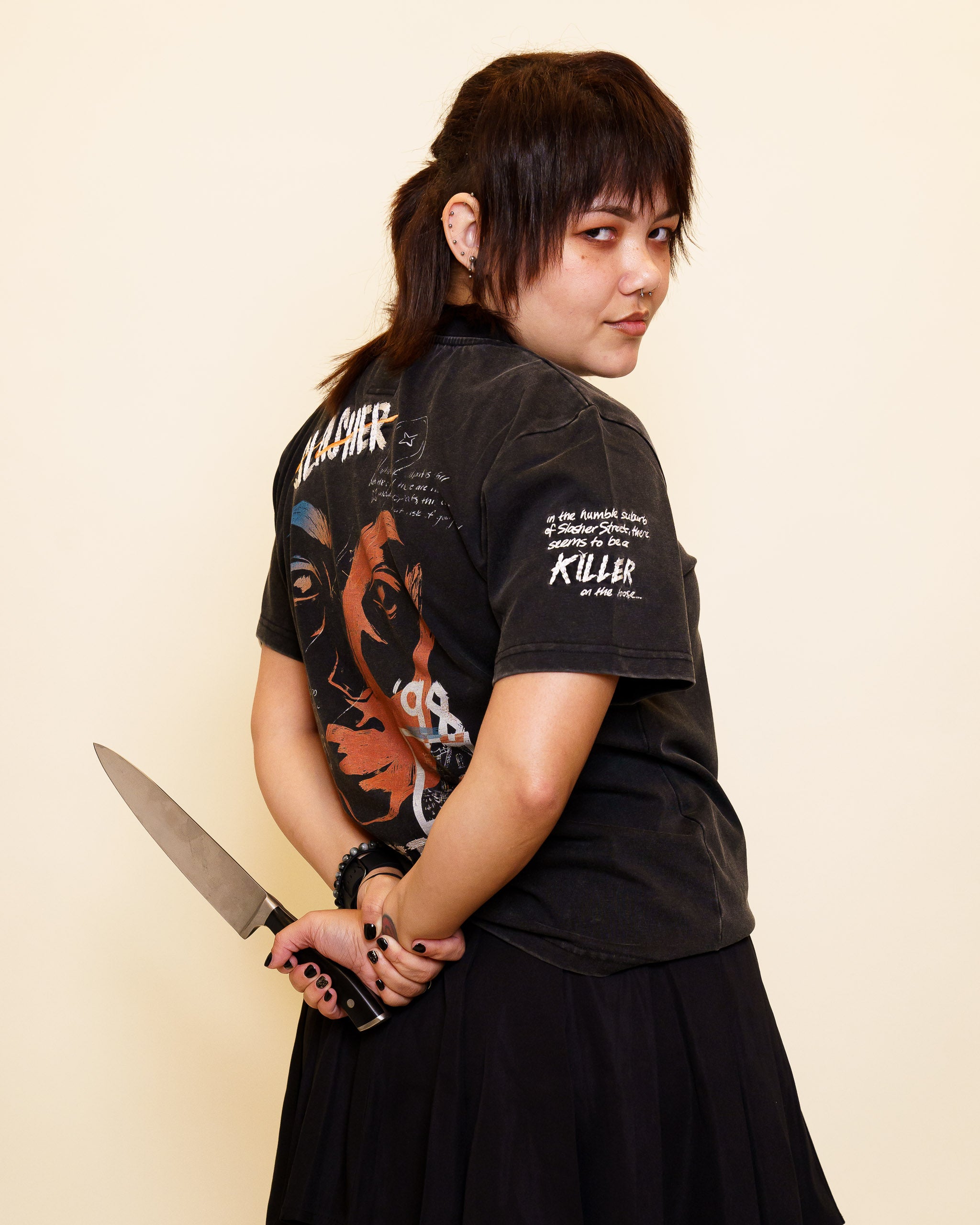 Woman wearing cold case tee in size 42 looking over the shoulder and holding a knife.