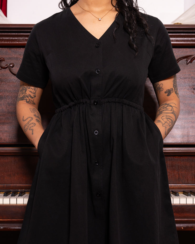 Front view of curtsy black smock dress.