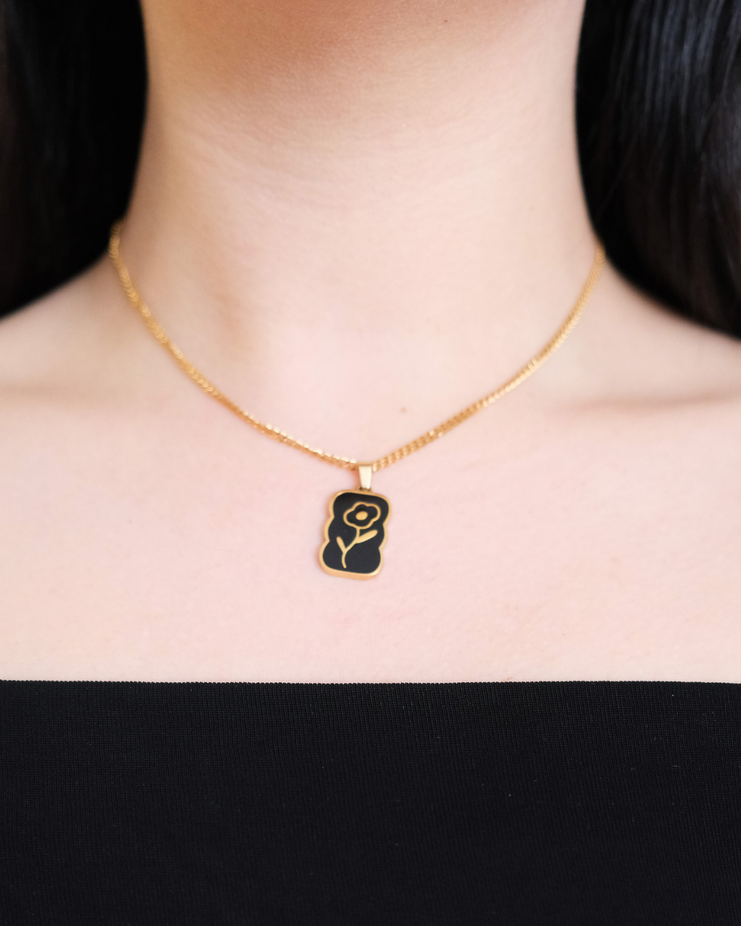 Daisy enamel pendant in gold being worn.