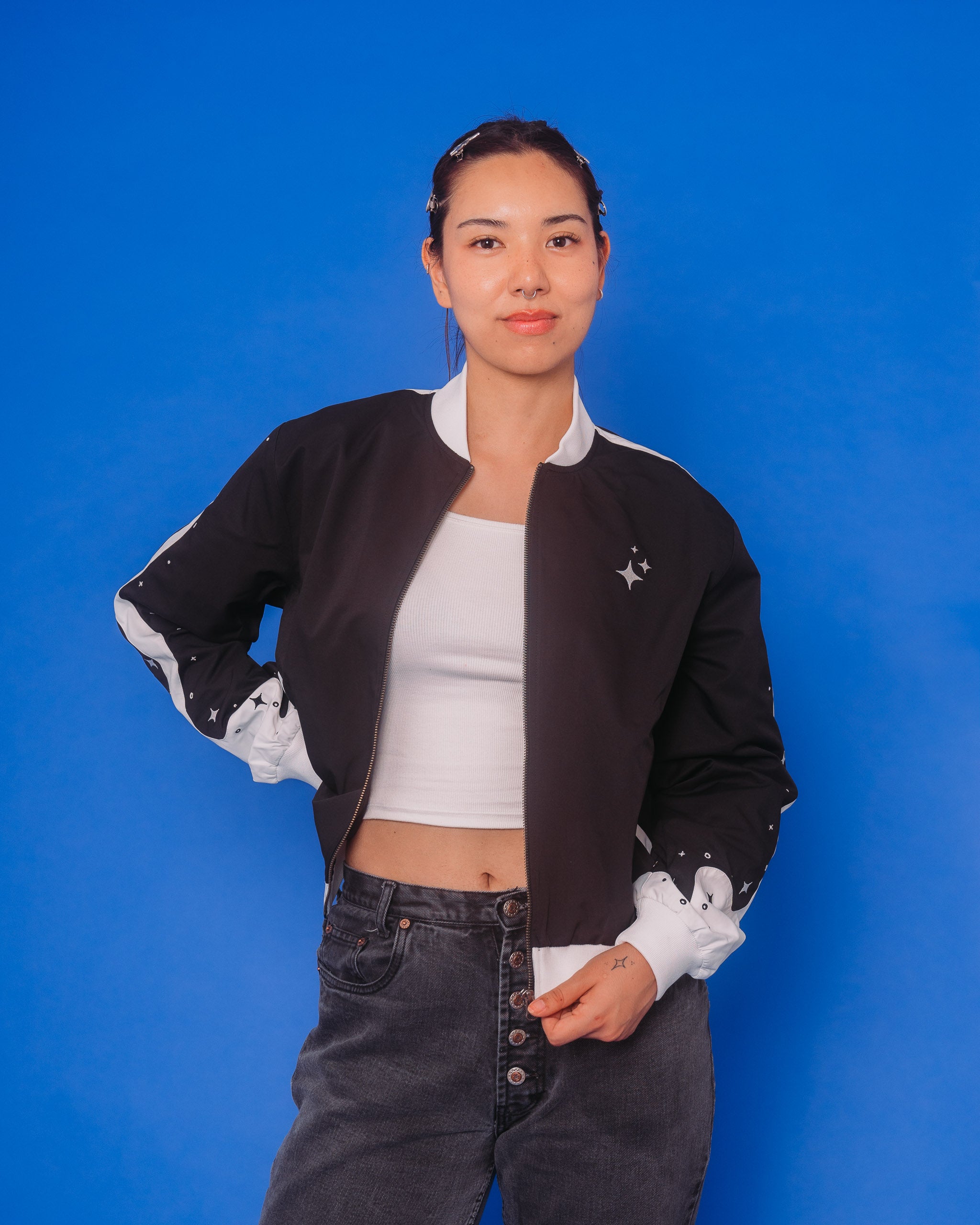 Woman wearing deep space bomber jacket in size medium in front of blue background.