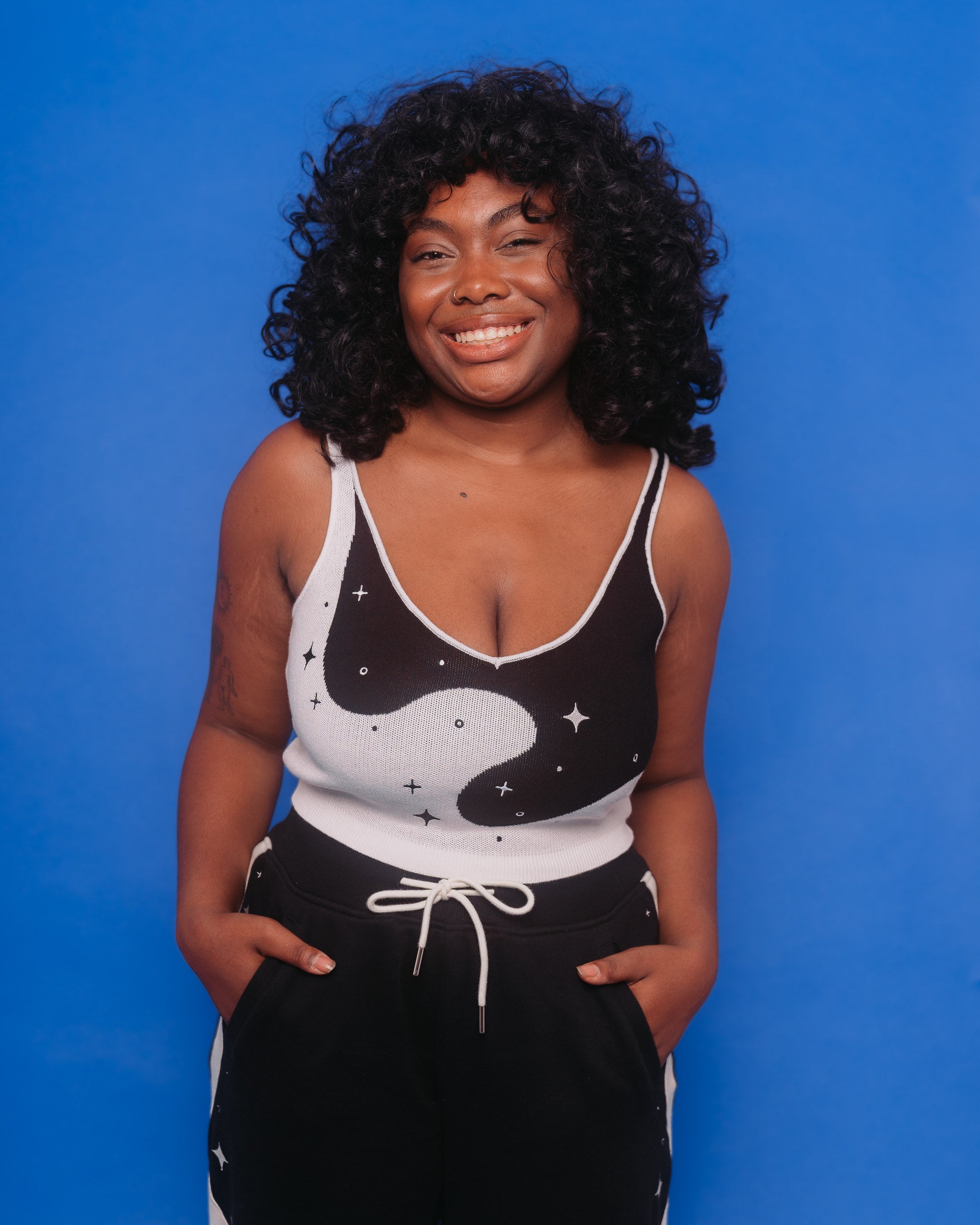 Woman wearing deep space knit tank in size large with deep space joggers in front of blue background.