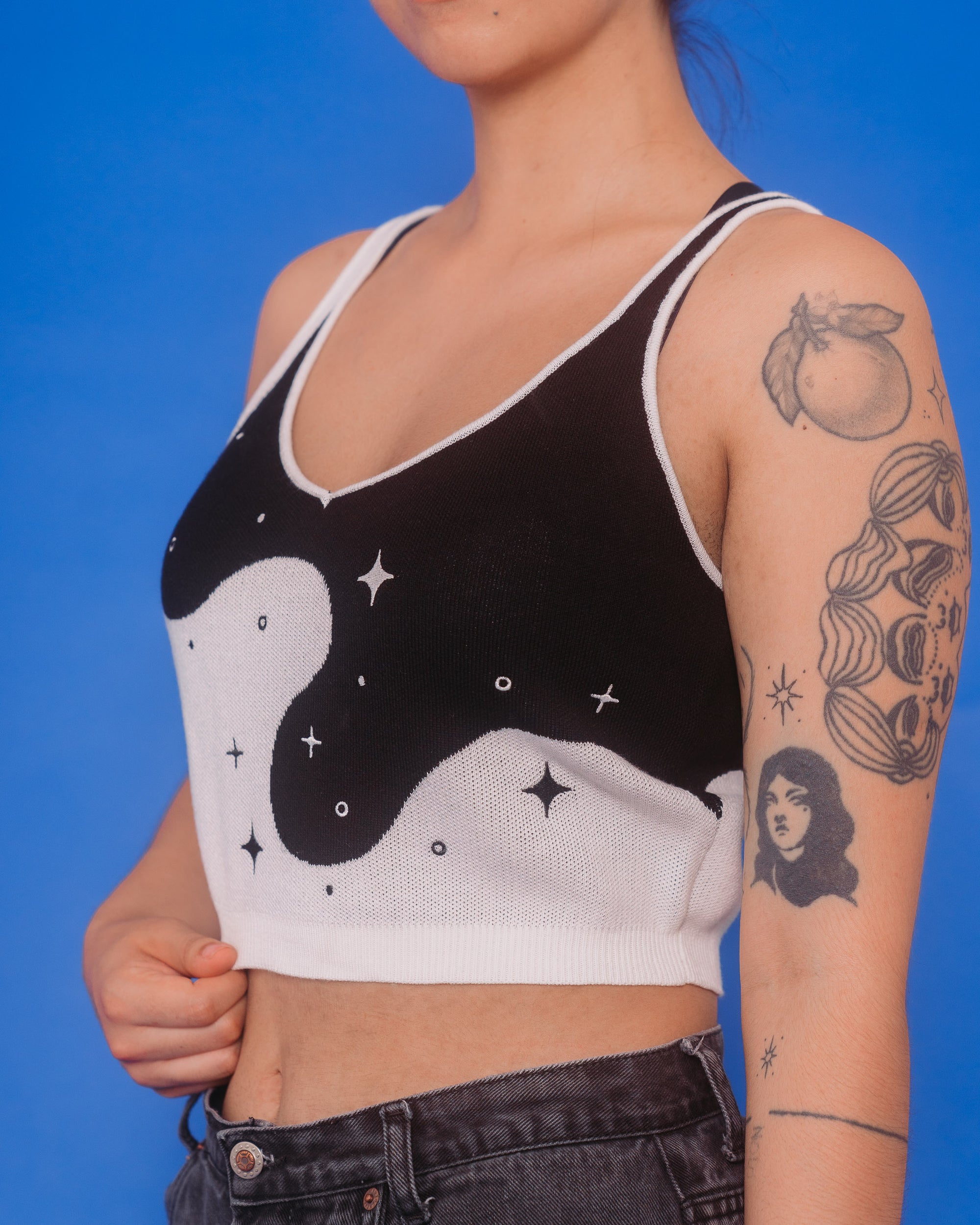 Woman wearing deep space knit tank in size medium showcasing embroidered sparkle details.
