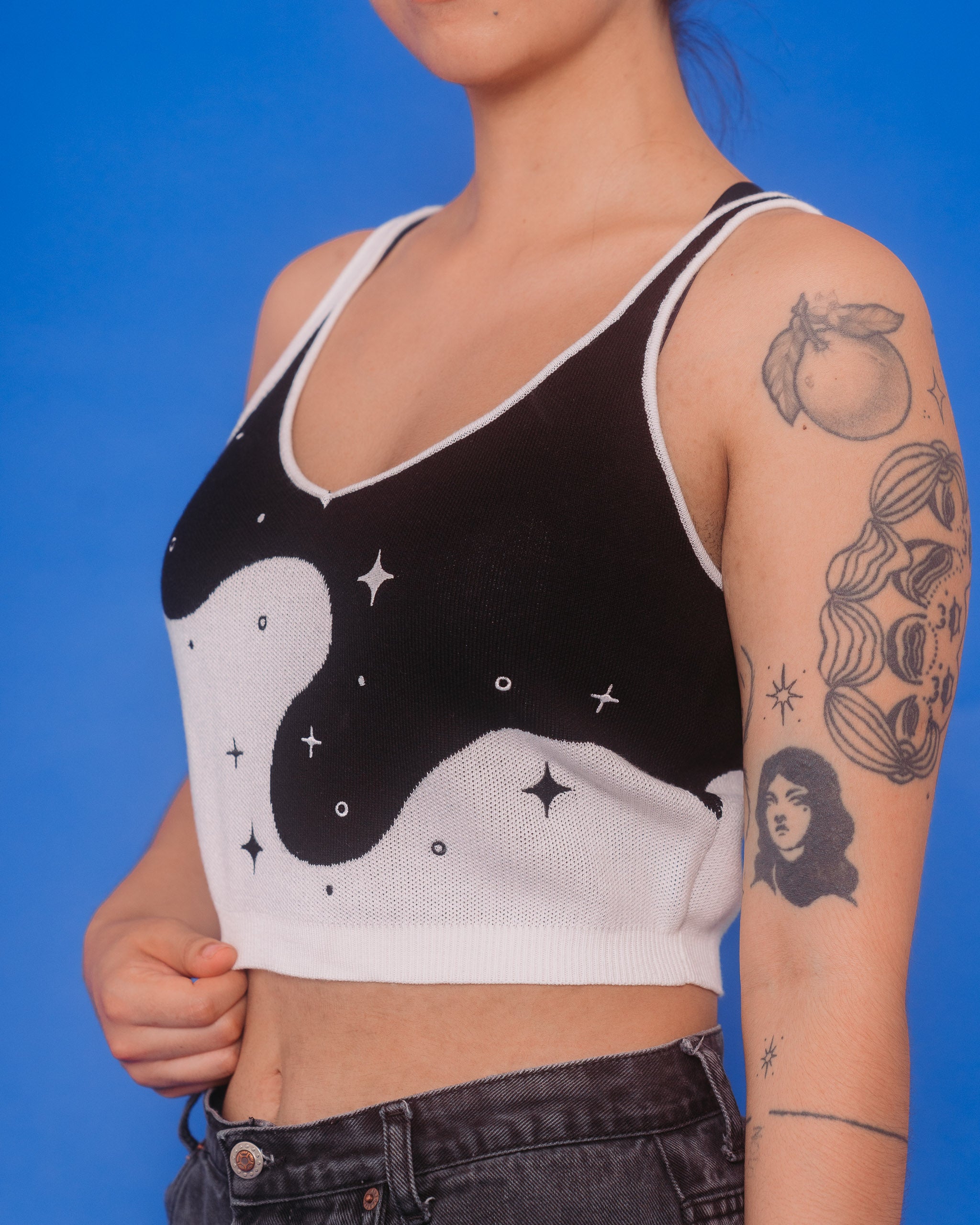 Woman wearing deep space knit tank in size medium showcasing embroidered sparkle details.