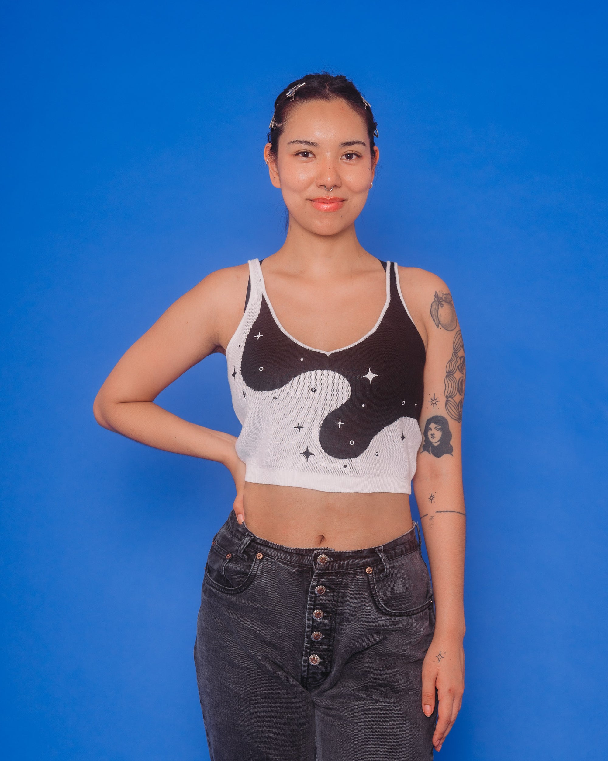 Woman wearing deep space knit tank in size medium in front of blue background.