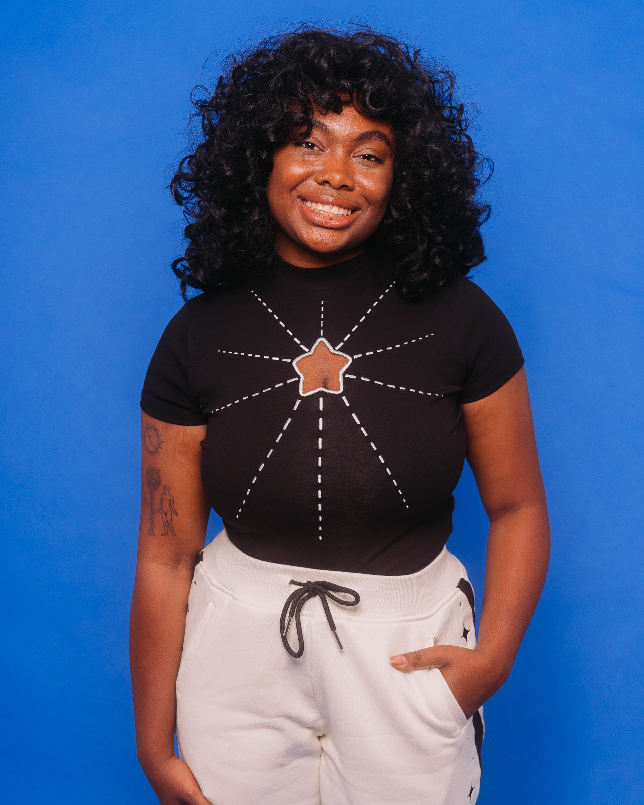 Woman wearing deep space mini tee in size large in front of blue background.