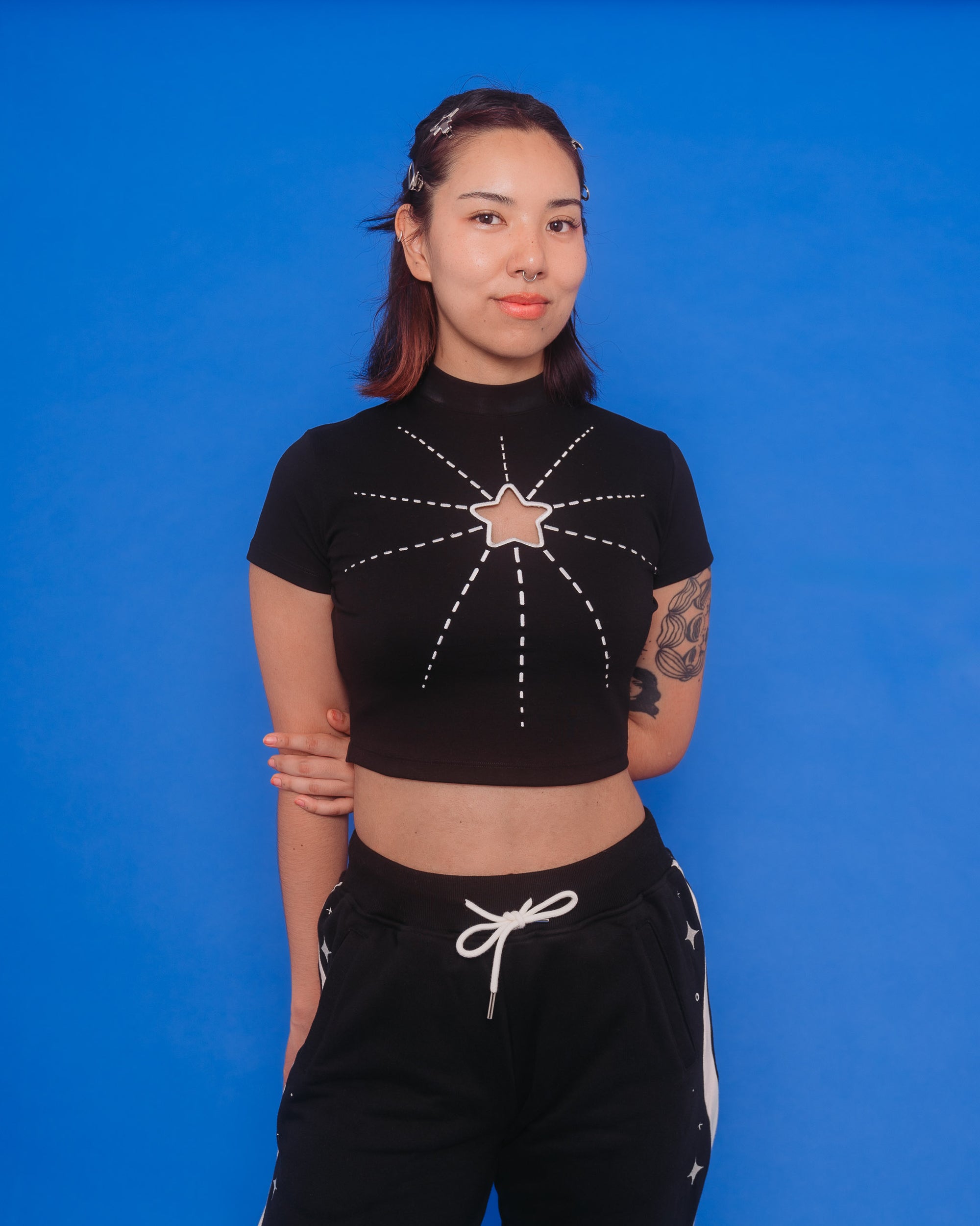 Woman wearing deep space mini tee in size medium in front of blue background.