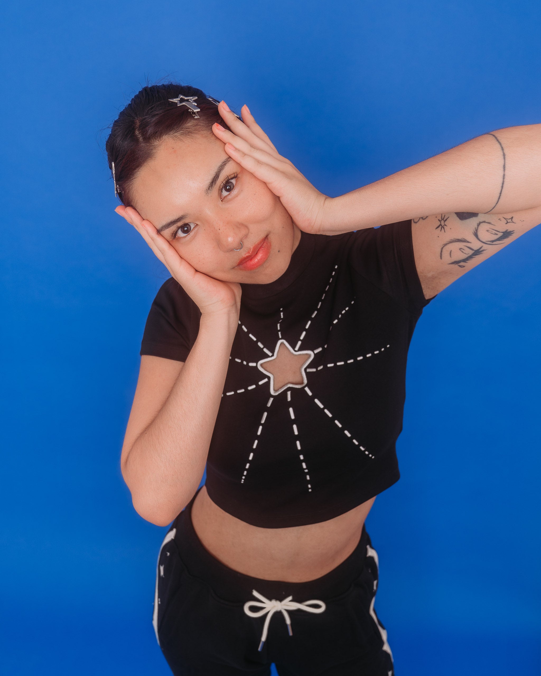 Woman wearing deep space mini tee in size medium posing in front of blue background.