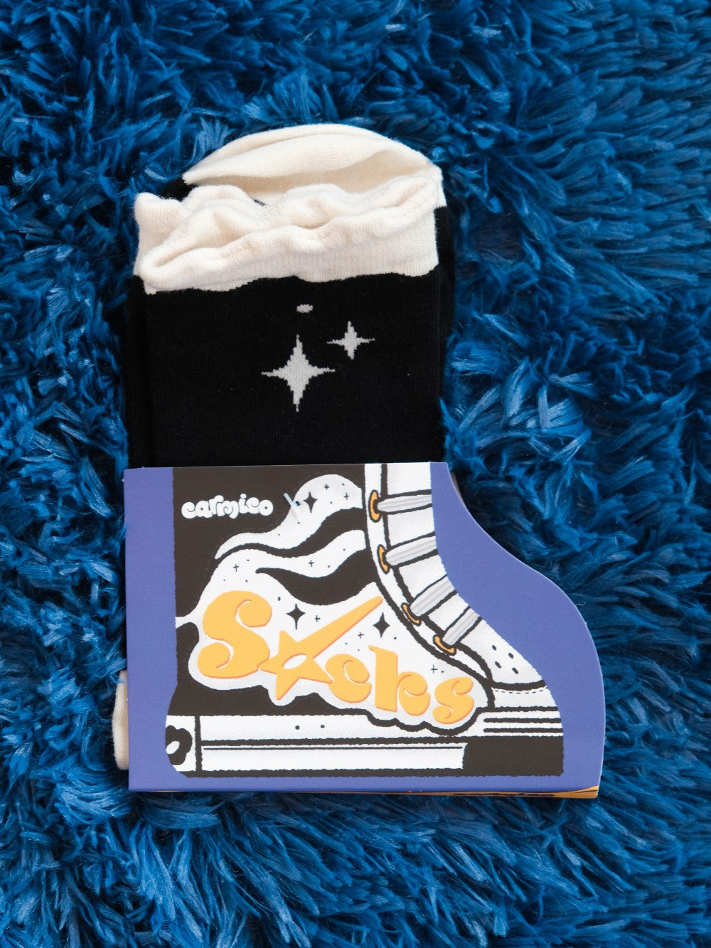 Deep space socks laying on fuzzy blue background in shoe-inspired packaging.