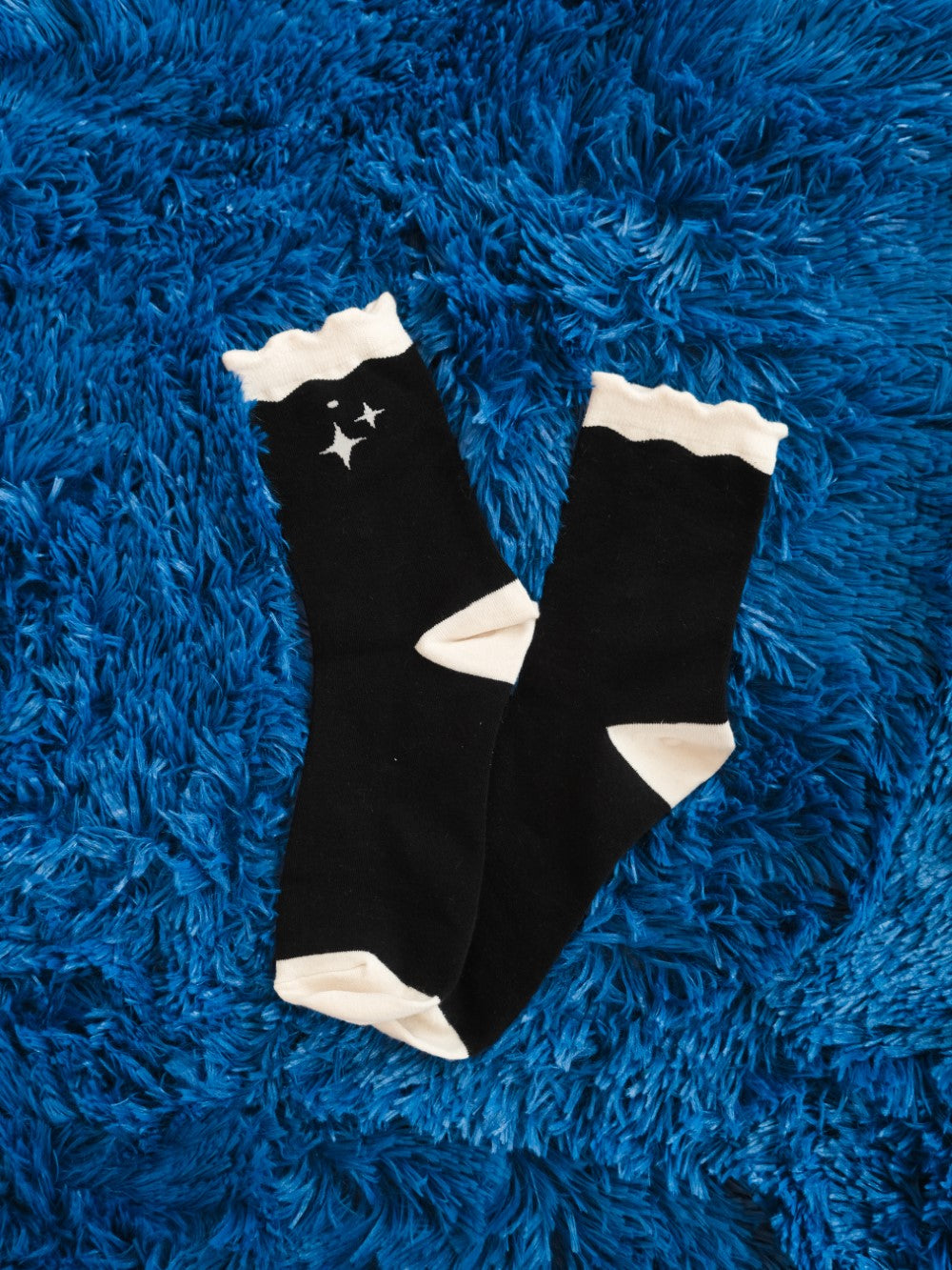 Pair of deep space socks laying on fuzzy blue background.