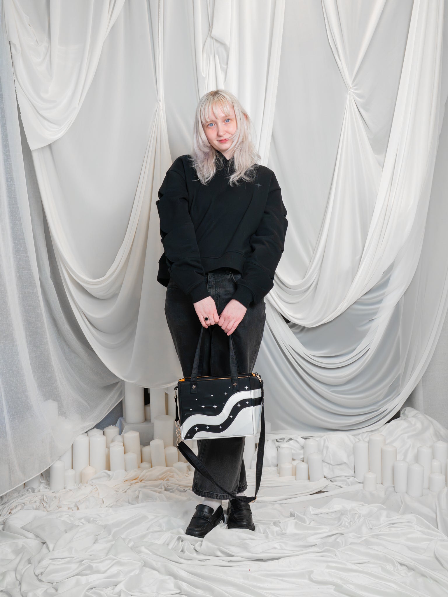 Deep space modular tote being carried by its short straps at knee length by a woman.