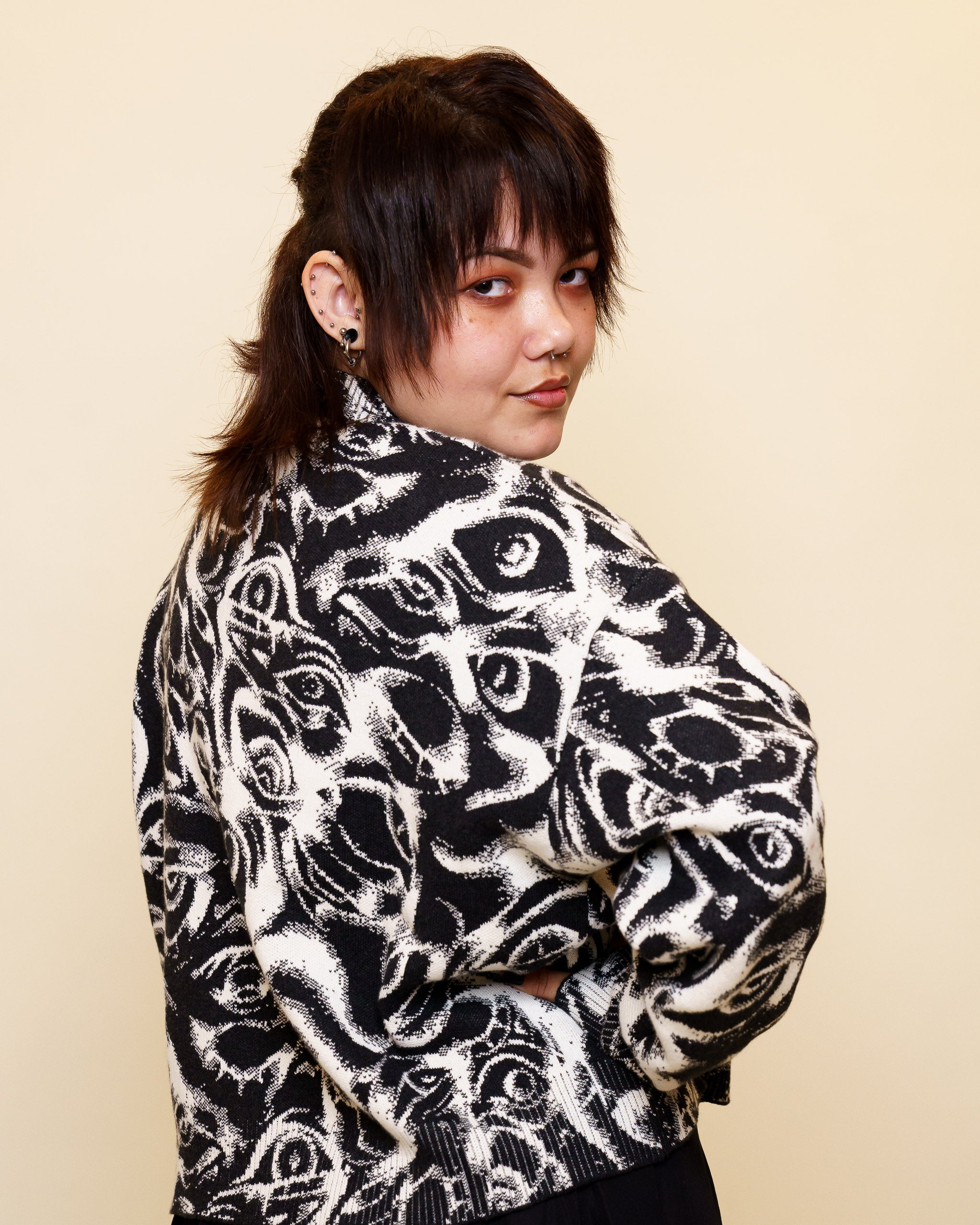 Woman wearing eyes on you cropped knit sweater in size medium glancing over the shoulder.