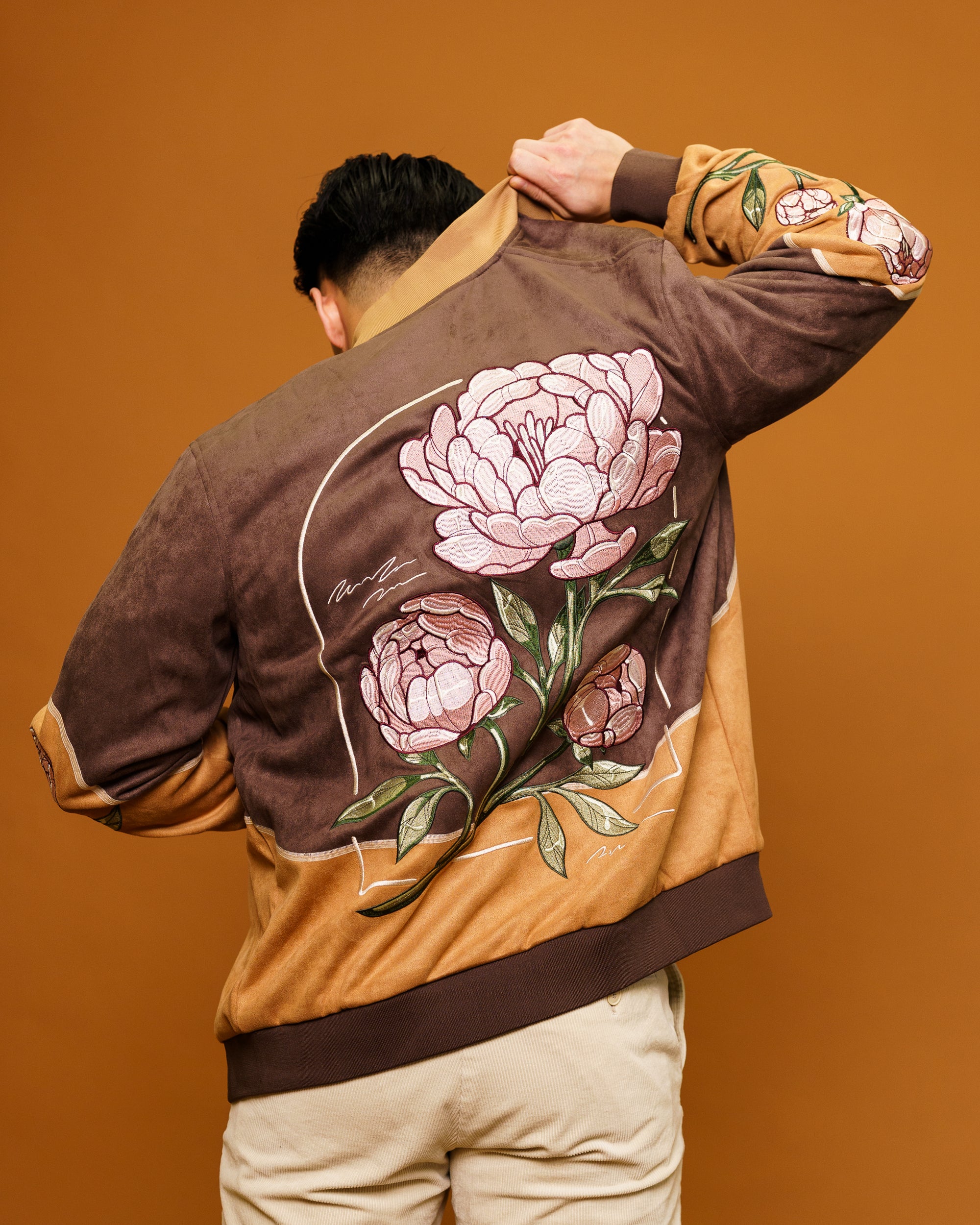 Back view of man wearing flowers for oscar jacket in size small, showcasing floral patch design on back.