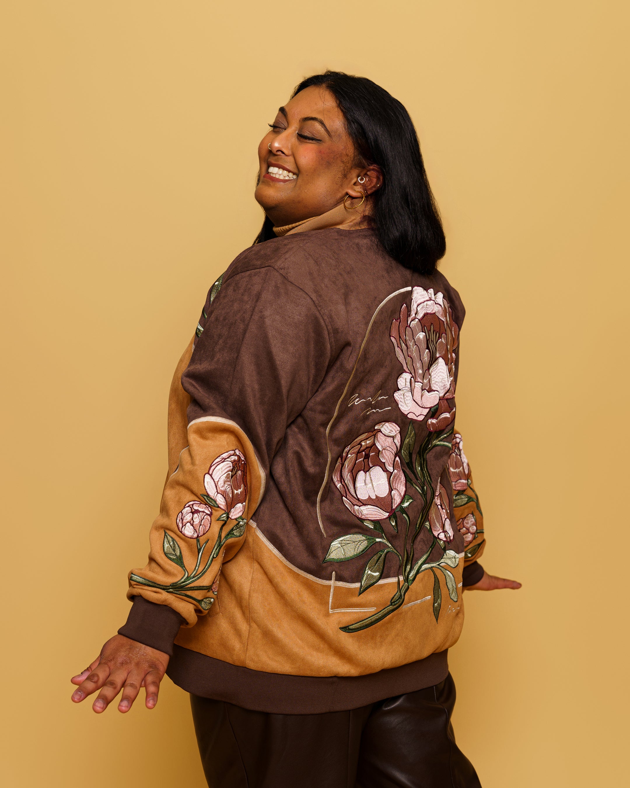 Side back view of woman wearing flowers for oscar faux-suede jacket in size extra large in front of soft yellow background.