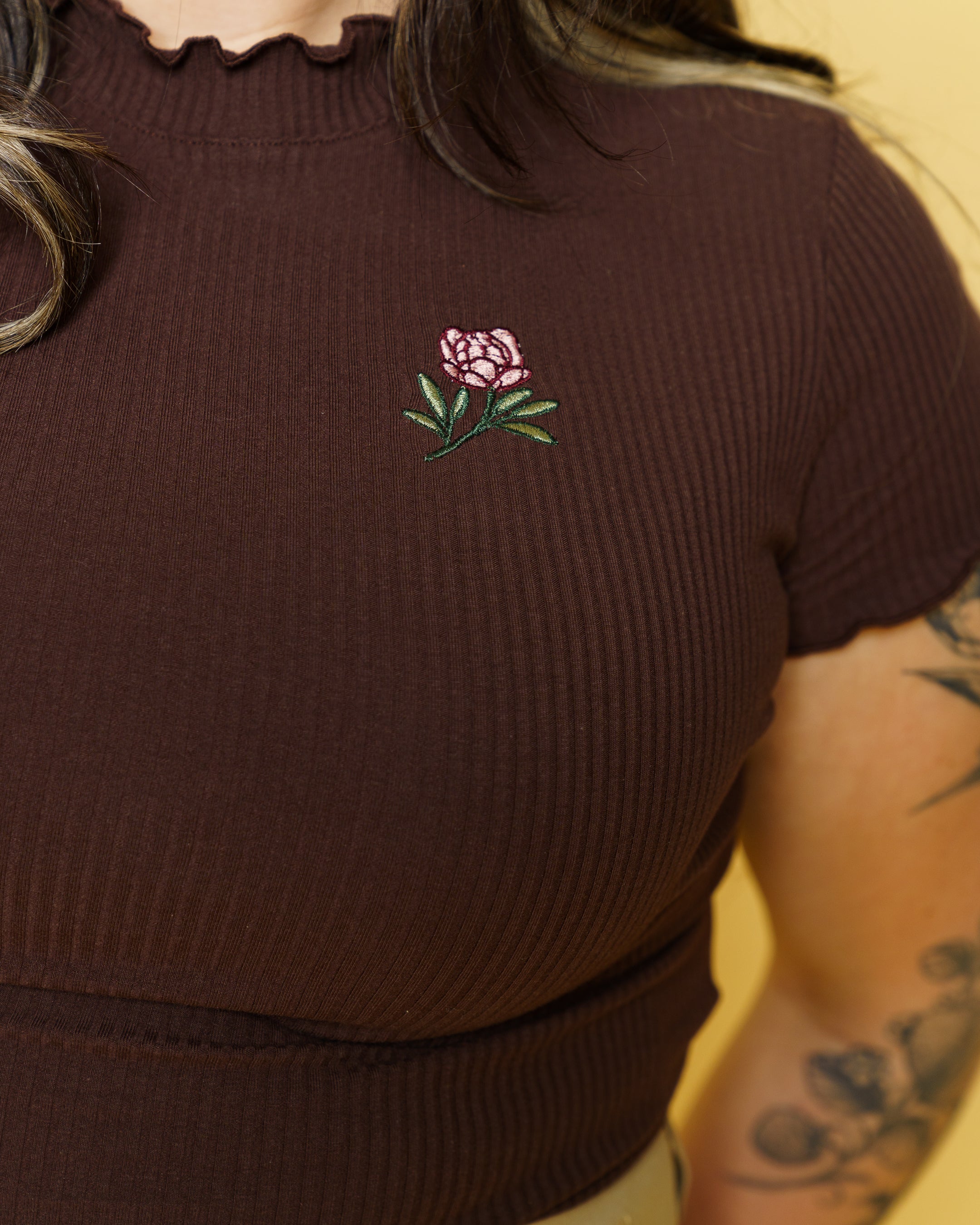 Close up of freshly picked brown mini tee embroidered flower detail.