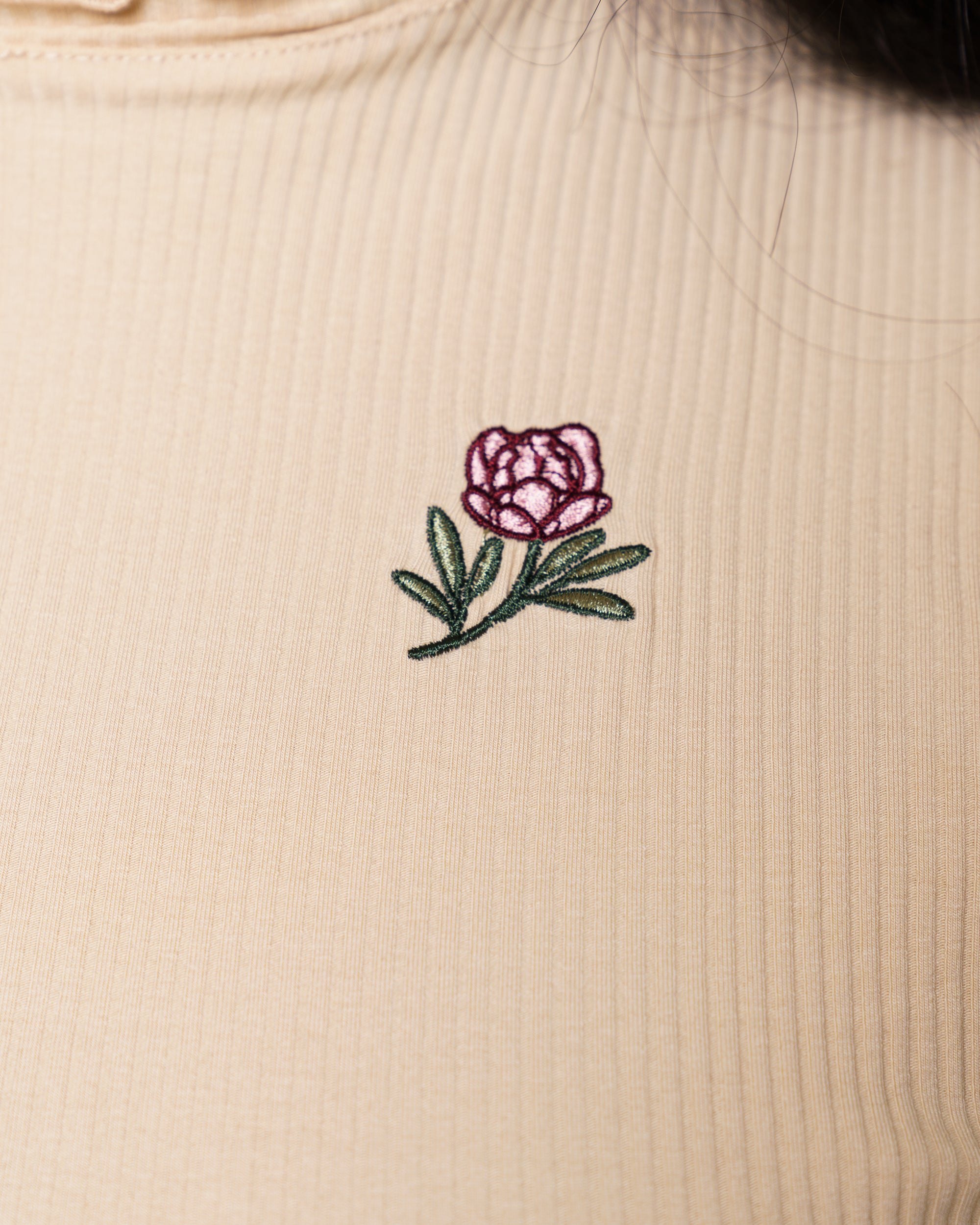 Close up of freshly picked cream mini tee embroidered flower detail.