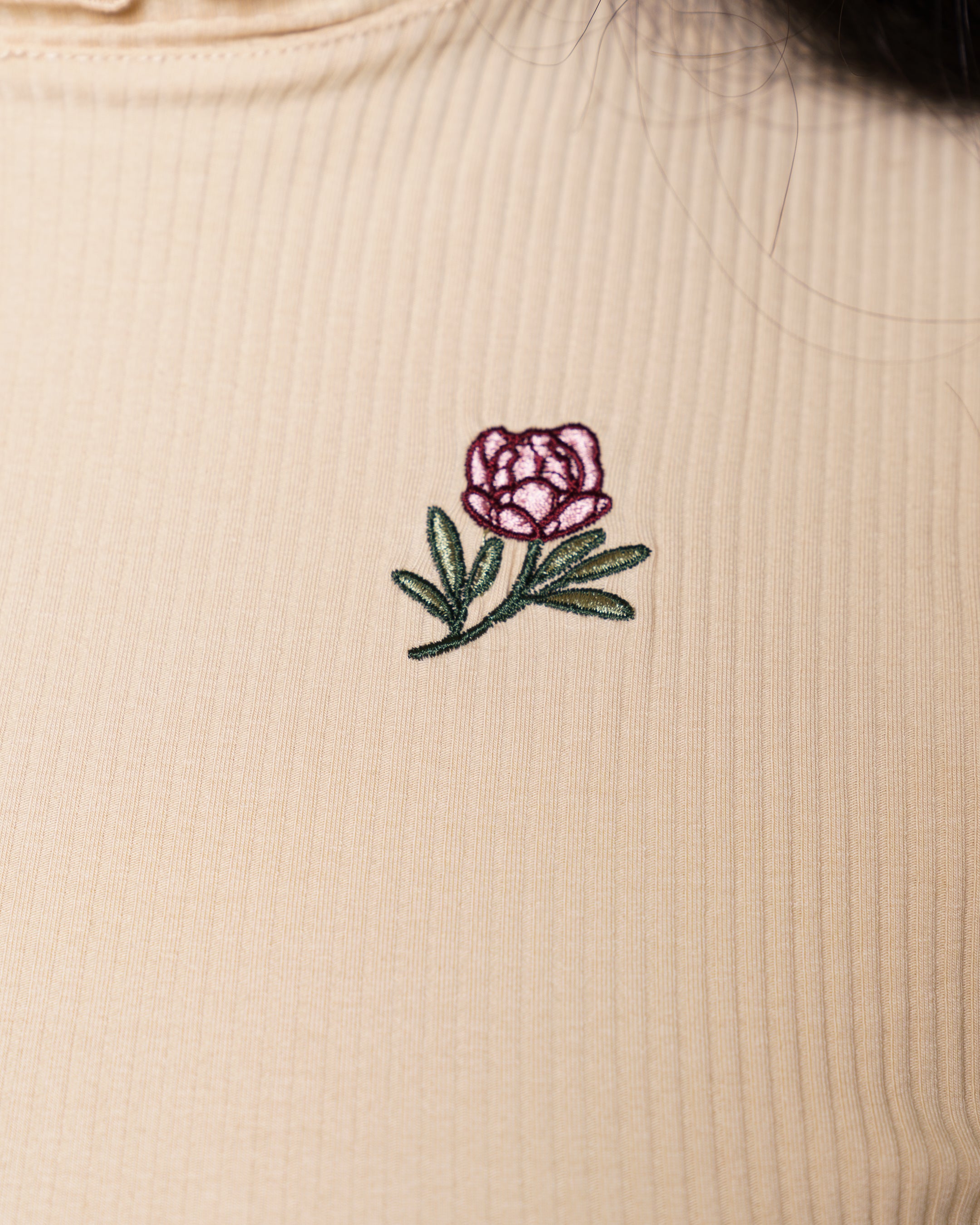 Close up of freshly picked cream mini tee embroidered flower detail.