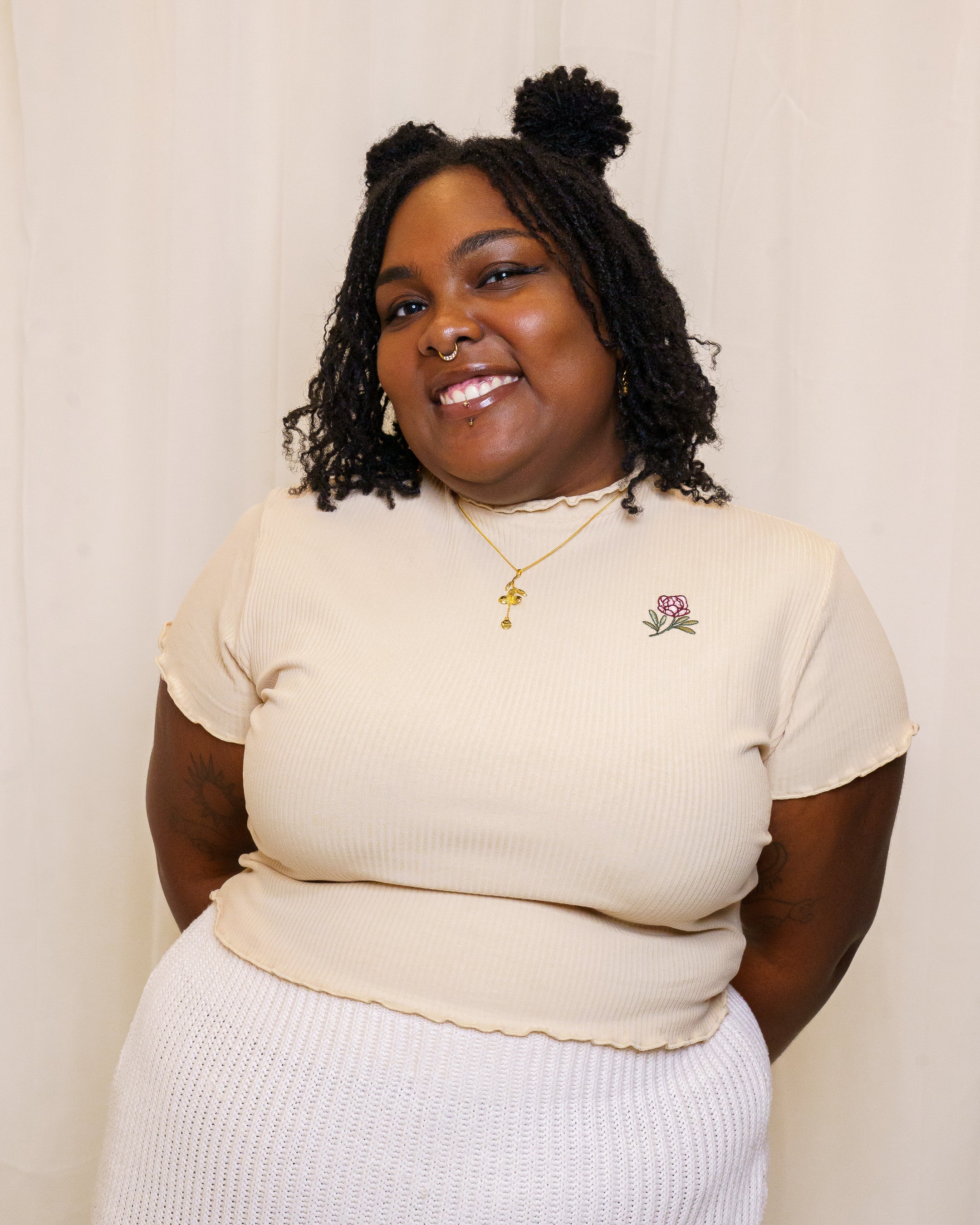 Woman wearing freshly picked cream mini tee in size extra large in front of white fabric.