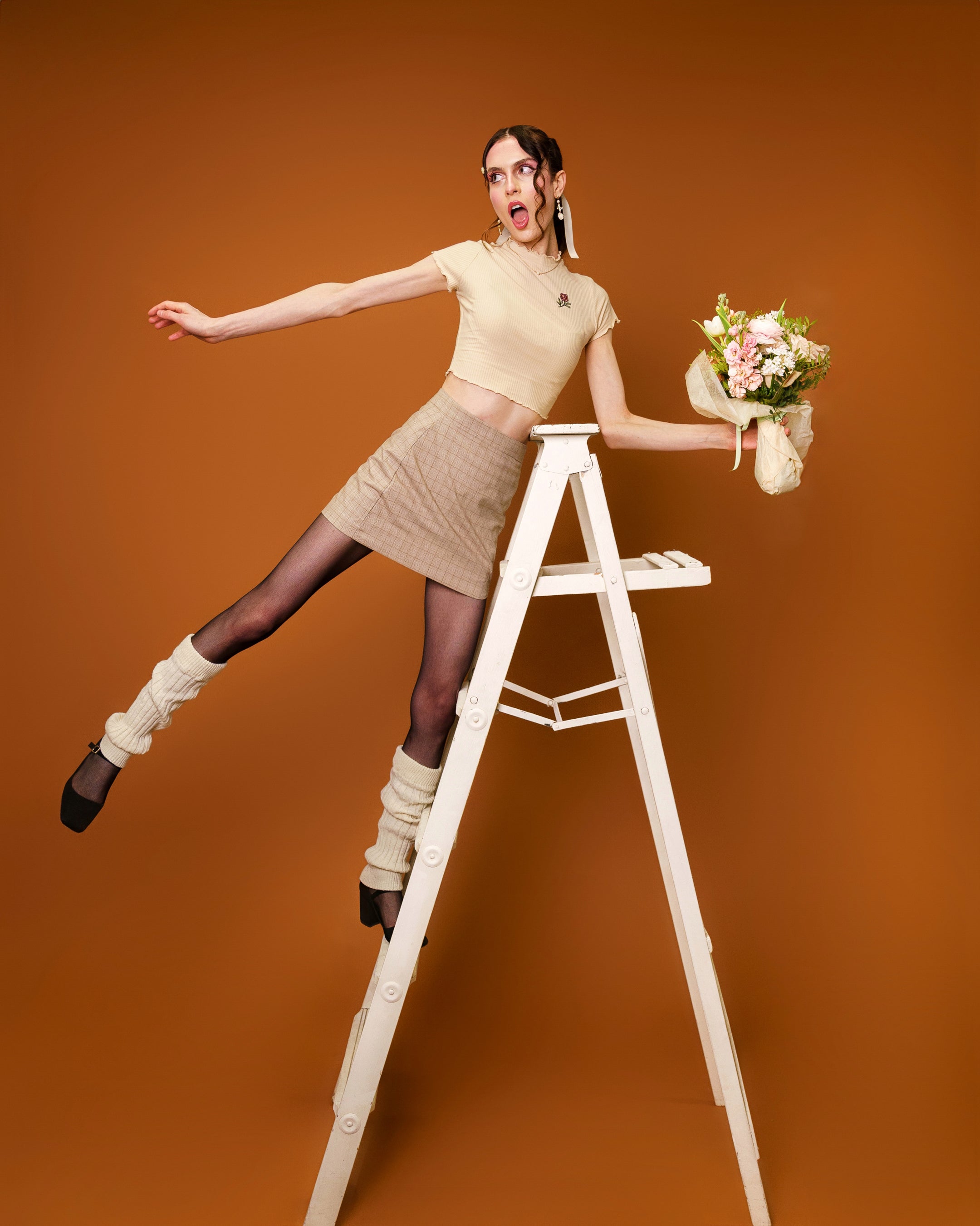 Woman wearing freshly picked cream mini tee in size extra small posing on ladder.