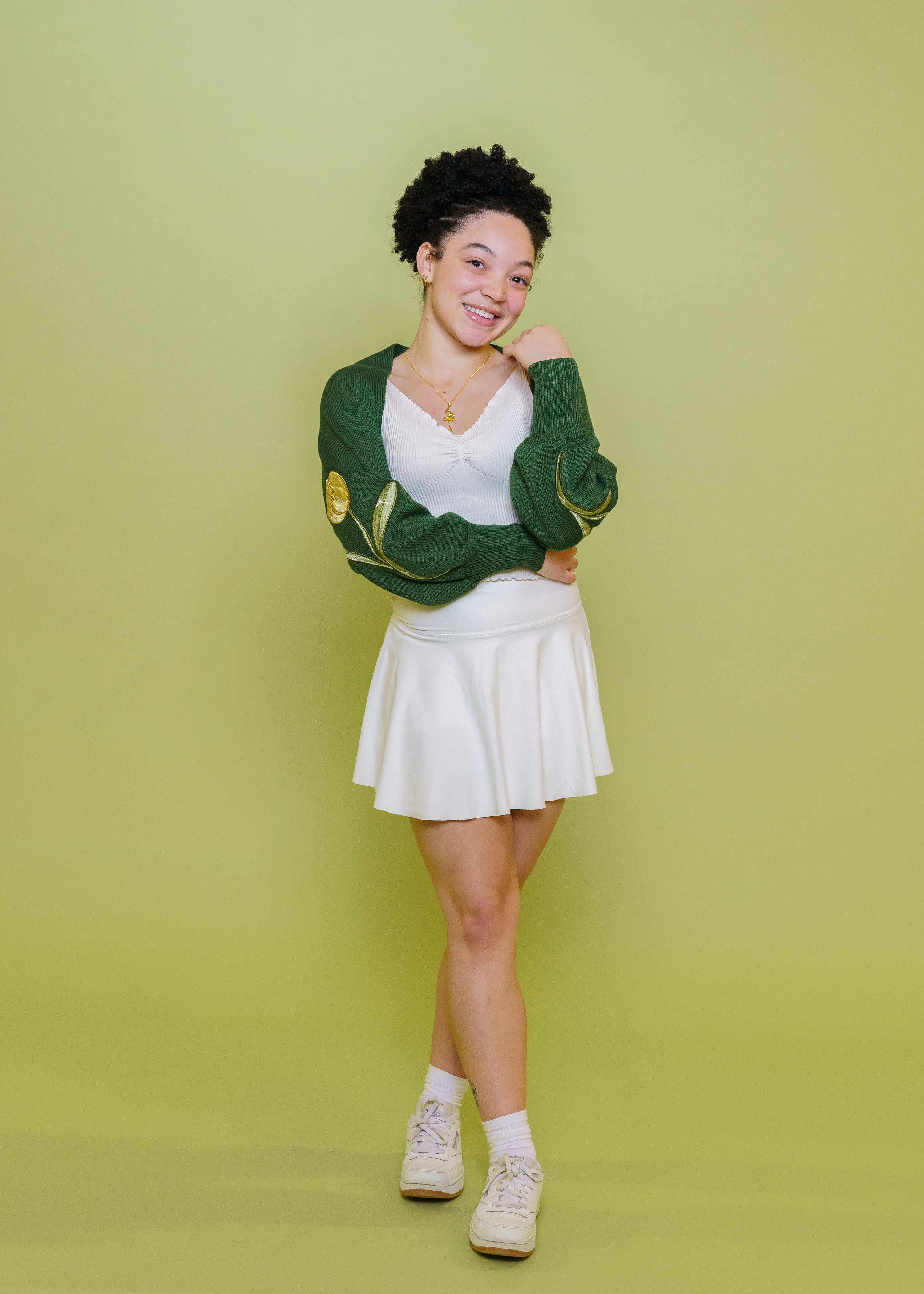 Woman wearing garden green bolero in front of green background.