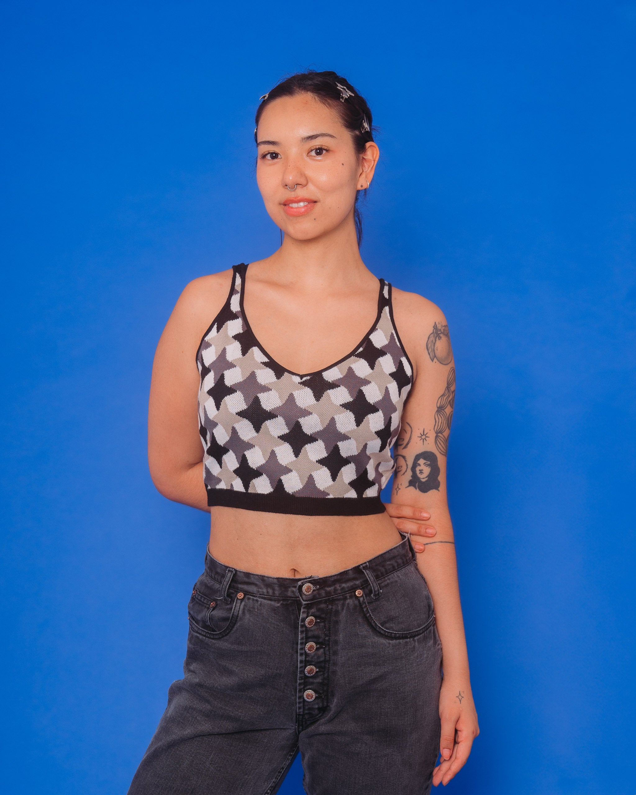 Woman wearing gunmetal knit tank in size medium in front of blue background.
