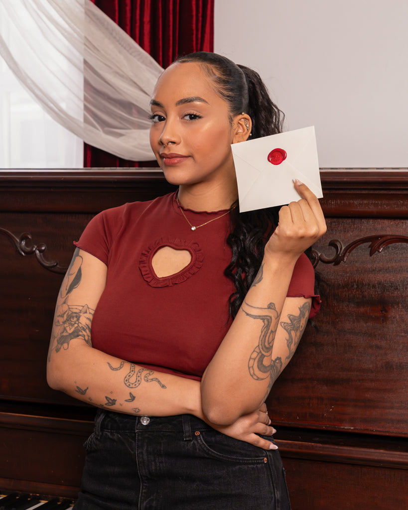 Woman wearing red heart throb mini tee in size small holding love letter.