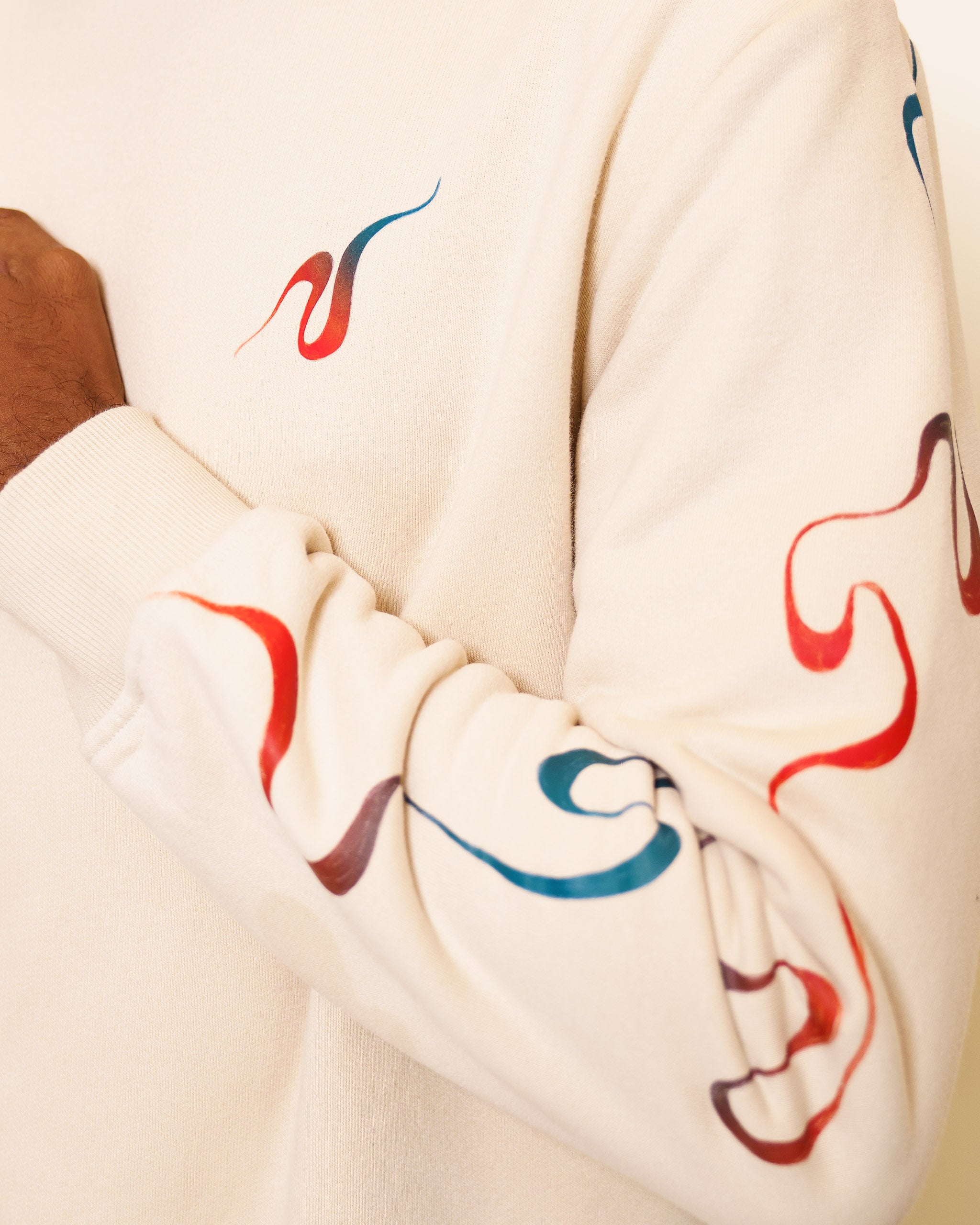 Close up of intuition crewneck sleeve details showing wavy red and blue gradient line flowing downwards.