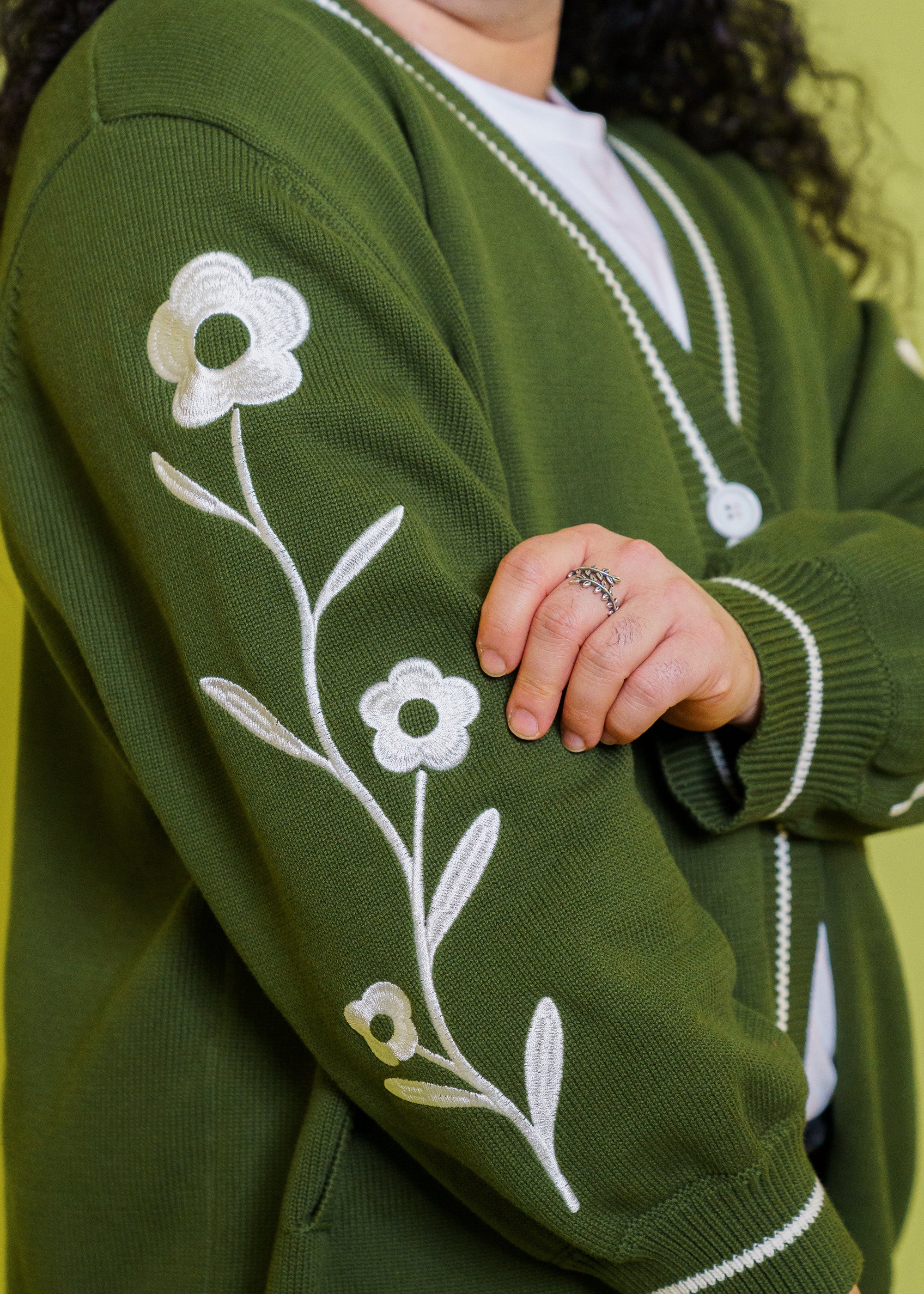 Close up of loose leaf cardigan sleeve side showcasing embroidered daisies.