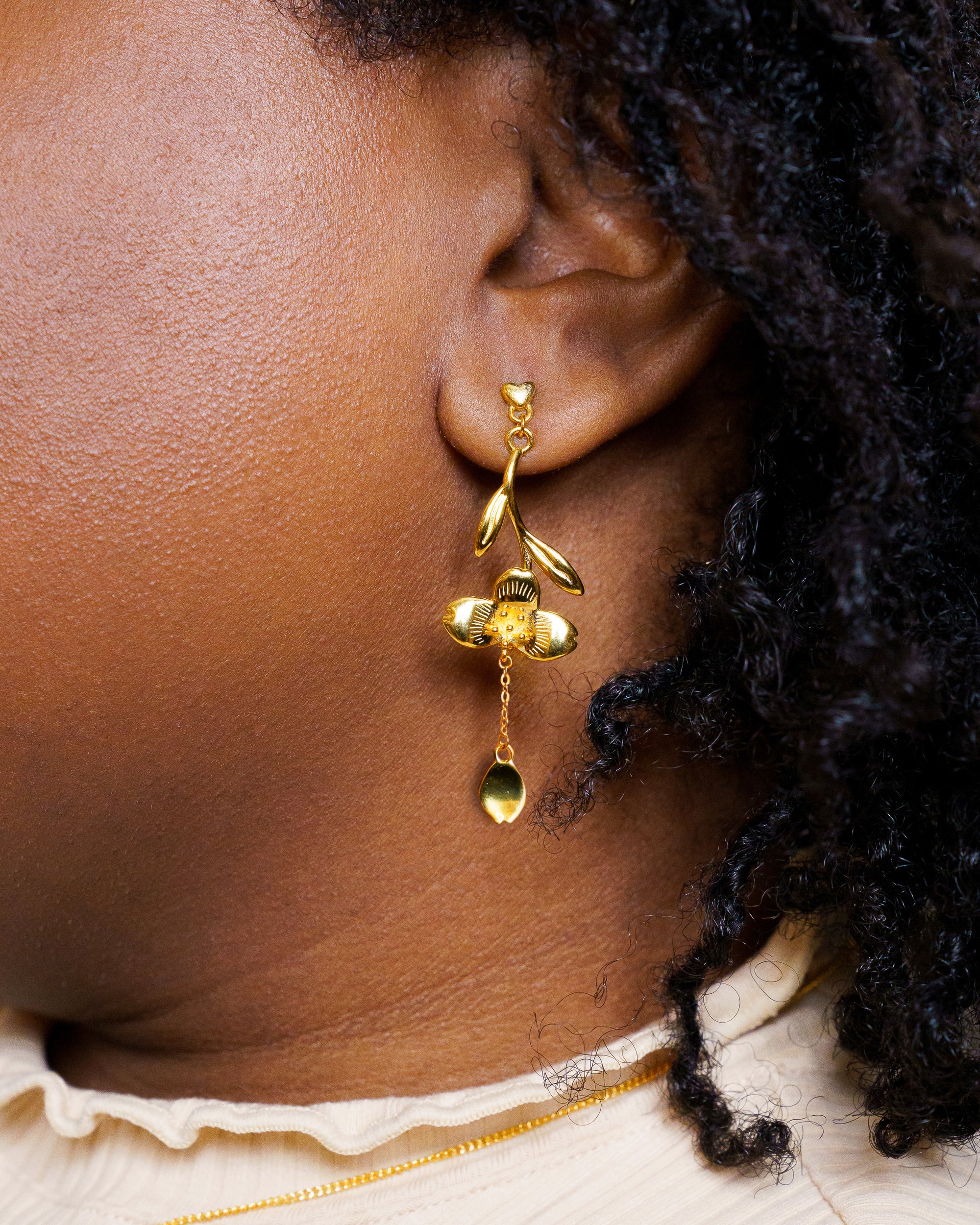 Woman wearing gold loves me not earrings.