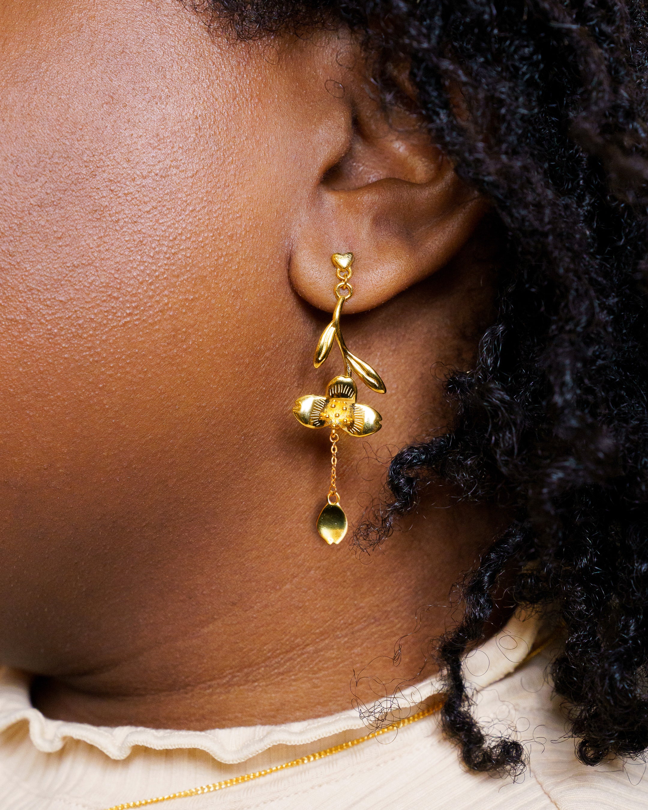 Woman wearing gold loves me not earrings.
