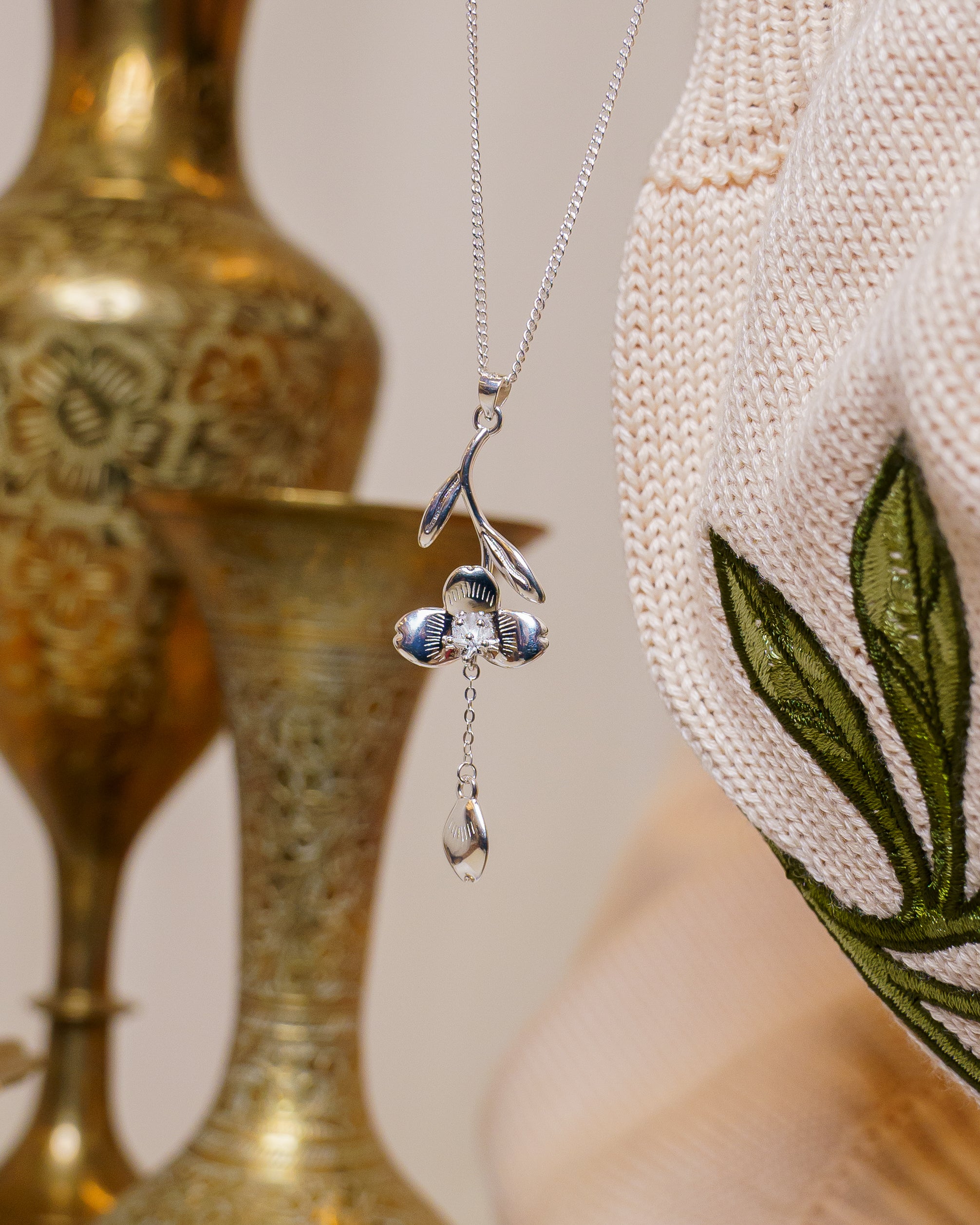 Close up of silver loves me not necklace hanging.